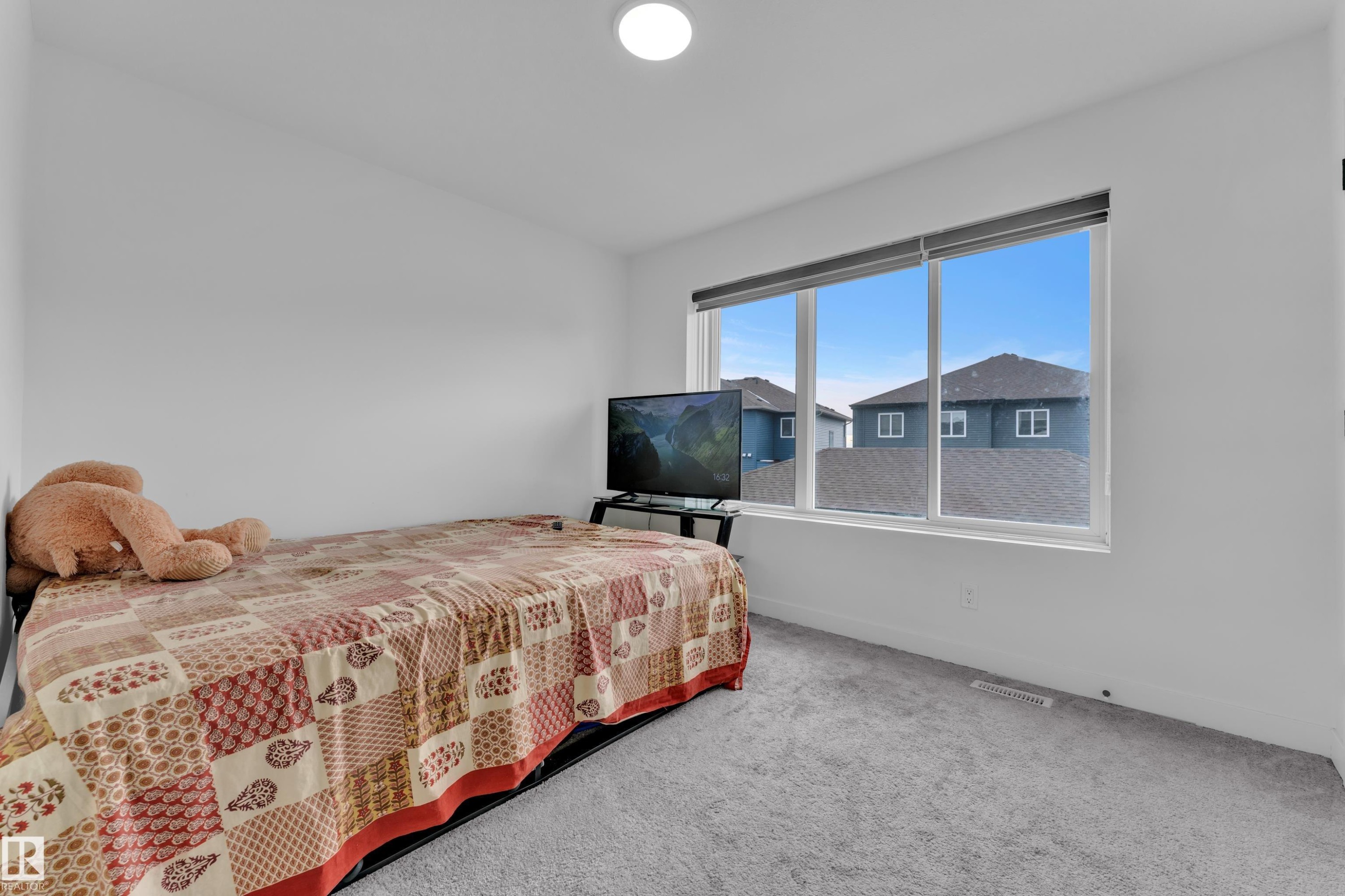 Room featuring light gray carpeting, a large window providing views of the neighborhood, and a ceiling light fixture - 1645 Plum Circle, Edmonton, AB - Indoor Photo Showing Bedroom