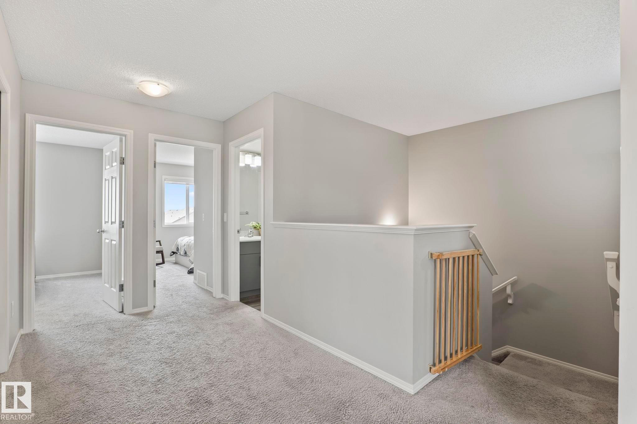 The property features a hallway with light grey carpet, white baseboards, and light grey walls - 5164 Lark Crescent Nw, Edmonton, AB - Indoor Photo Showing Other Room