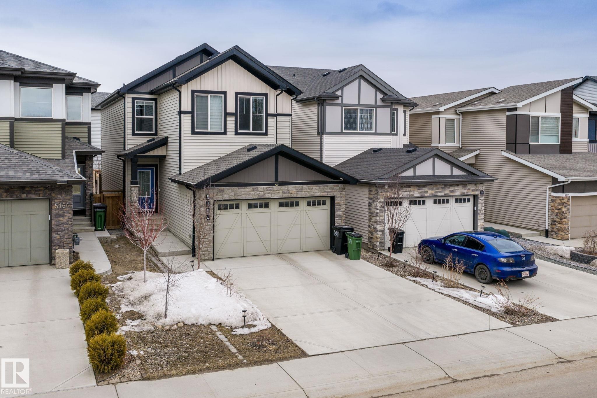 The property features a two-story exterior with light-colored siding, dark trim, and stone accents - 5164 Lark Crescent Nw, Edmonton, AB - Outdoor With Facade