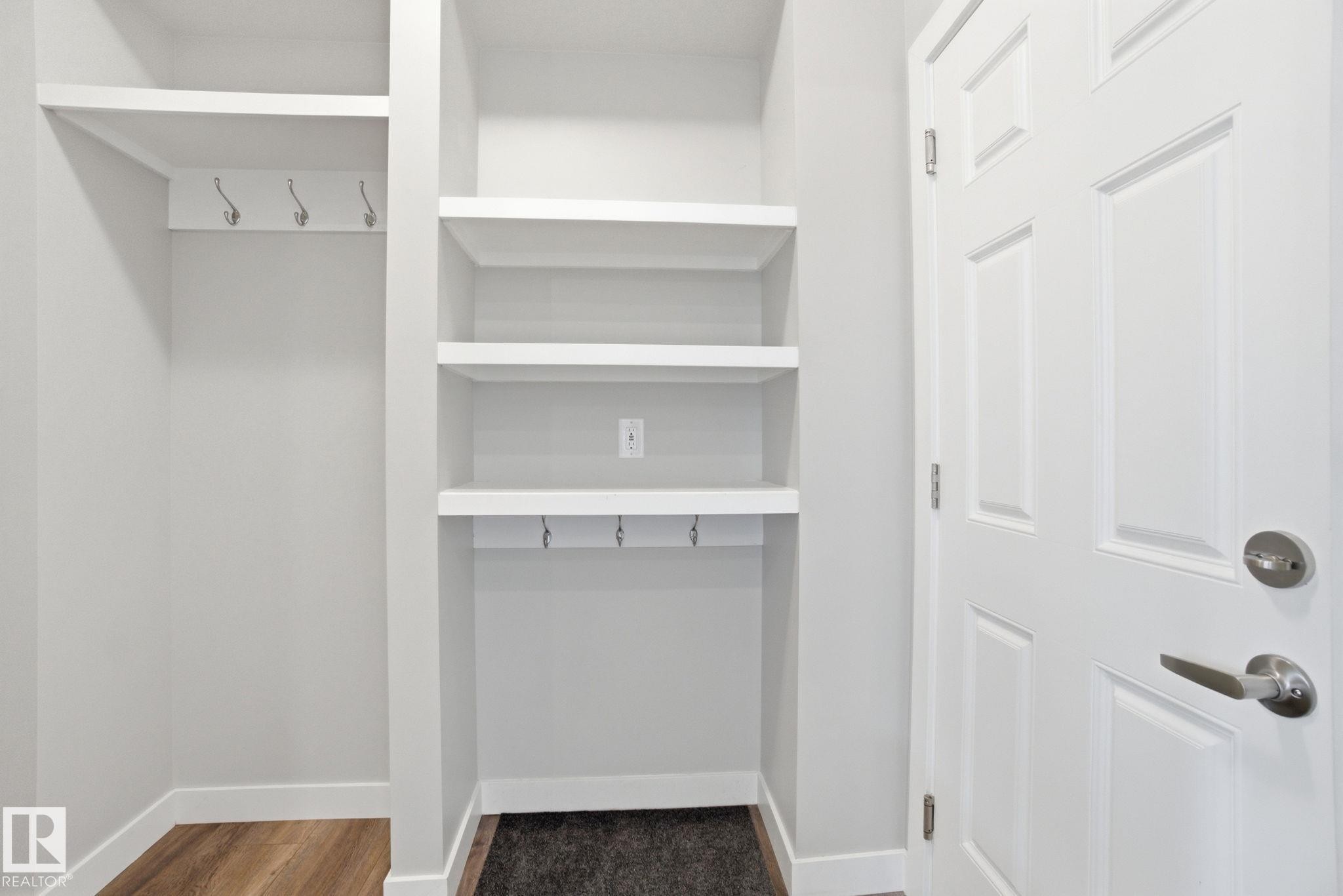 Entryway area featuring built-in shelving, wall hooks, and a paneled door with a brushed nickel handle - 1607 202 Street, Edmonton, AB - Indoor With Storage