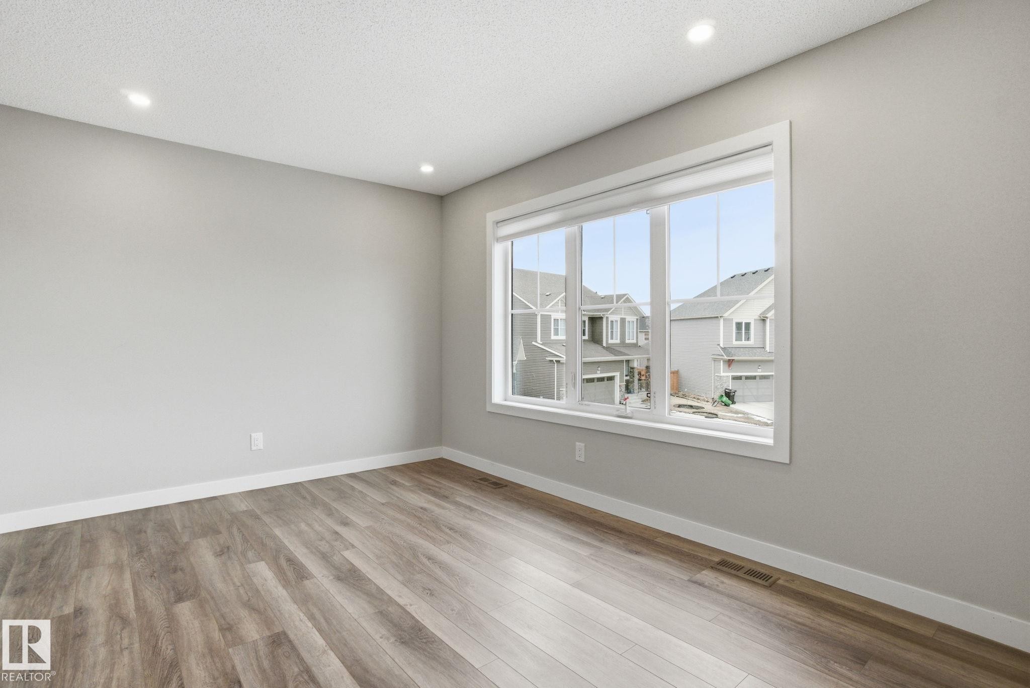 Spacious room with light-colored walls, recessed ceiling lighting, and a large window providing ample natural light - 1607 202 Street, Edmonton, AB - Indoor Photo Showing Other Room