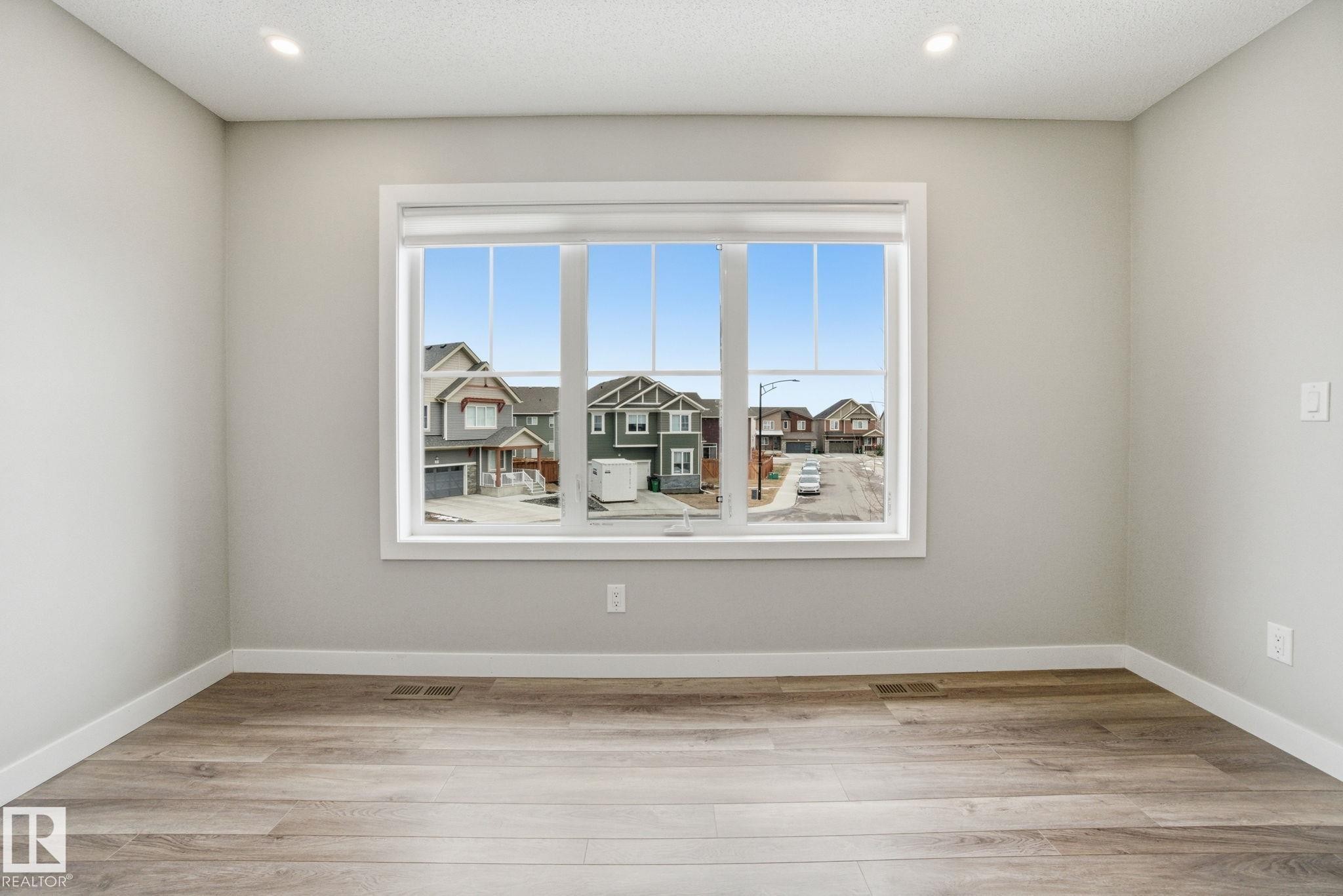 This room features light-colored walls and wood-style flooring, creating a bright and inviting atmosphere - 1607 202 Street, Edmonton, AB - Indoor Photo Showing Other Room