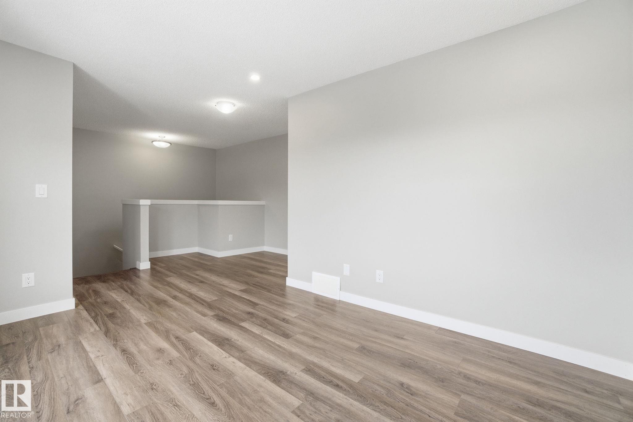 The property features light-colored walls, wood-style flooring, and recessed lighting fixtures, creating a bright and inviting space - 1607 202 Street, Edmonton, AB - Indoor Photo Showing Other Room