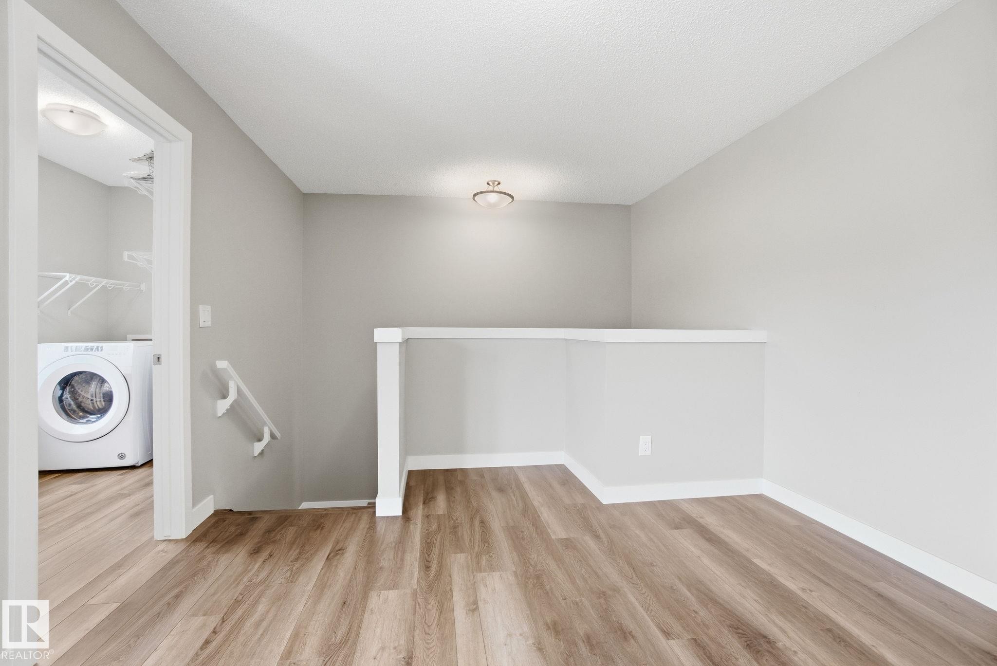 This area features light-toned walls, wood-style flooring, and a ceiling light fixture - 1607 202 Street, Edmonton, AB - Indoor