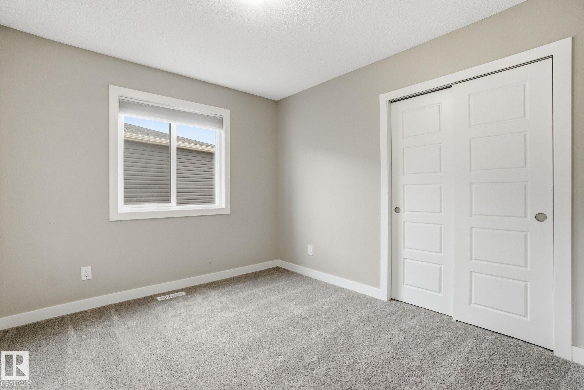 This room features neutral-toned walls, gray carpeting, and a window with a white frame - 1607 202 Street, Edmonton, AB - Indoor Photo Showing Other Room