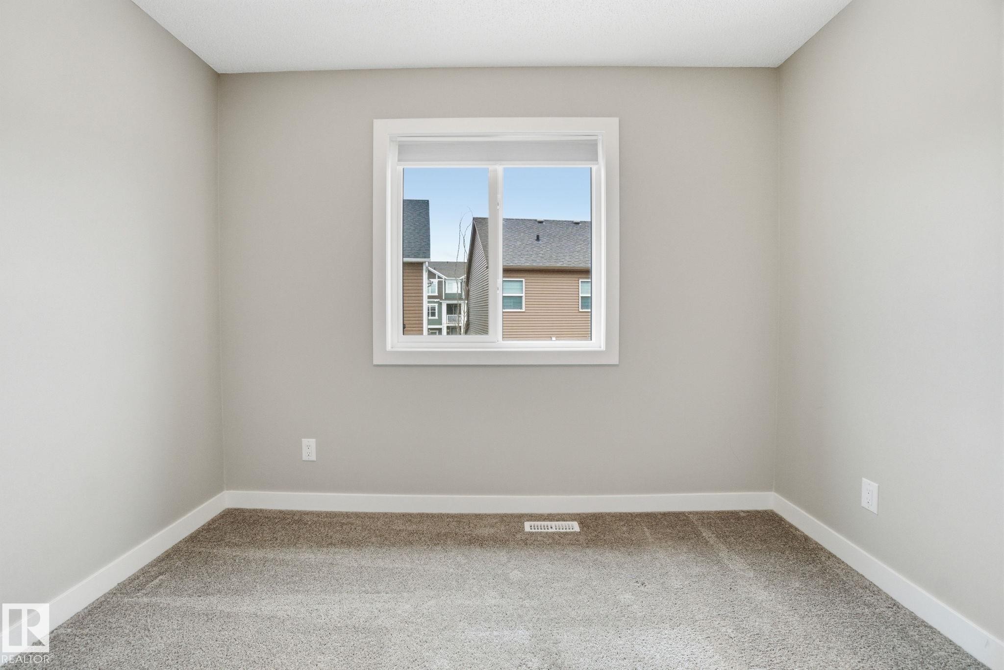The room features neutral-toned walls, a window with white trim, and light grey carpet flooring - 1607 202 Street, Edmonton, AB - Indoor Photo Showing Other Room