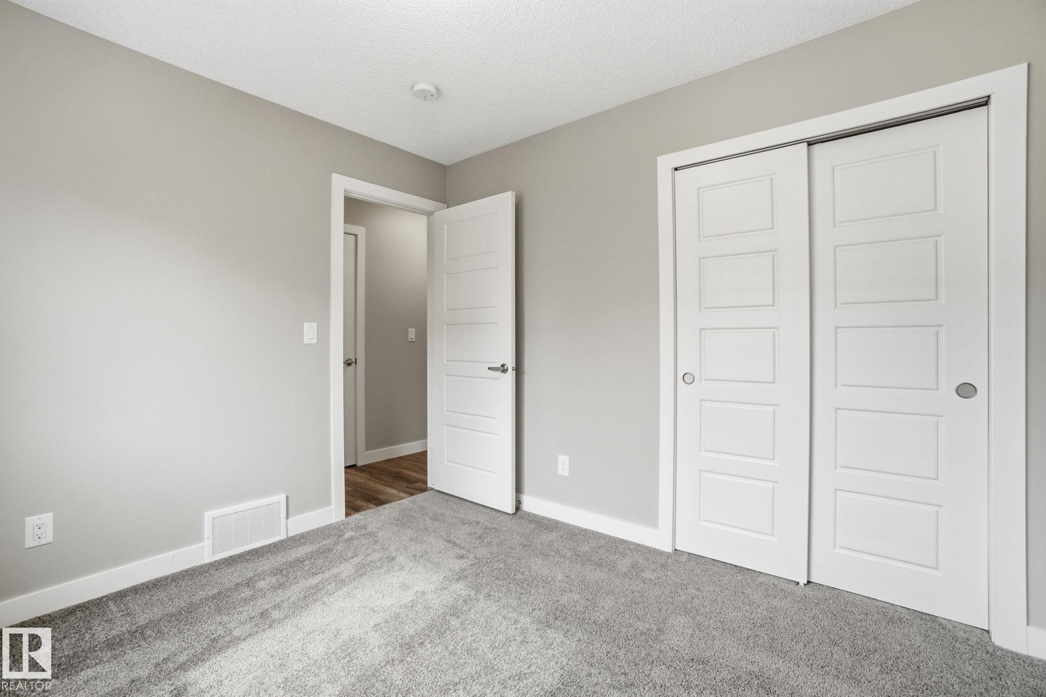 This room features neutral gray walls, plush gray carpeting, and white trim - 1607 202 Street, Edmonton, AB - Indoor