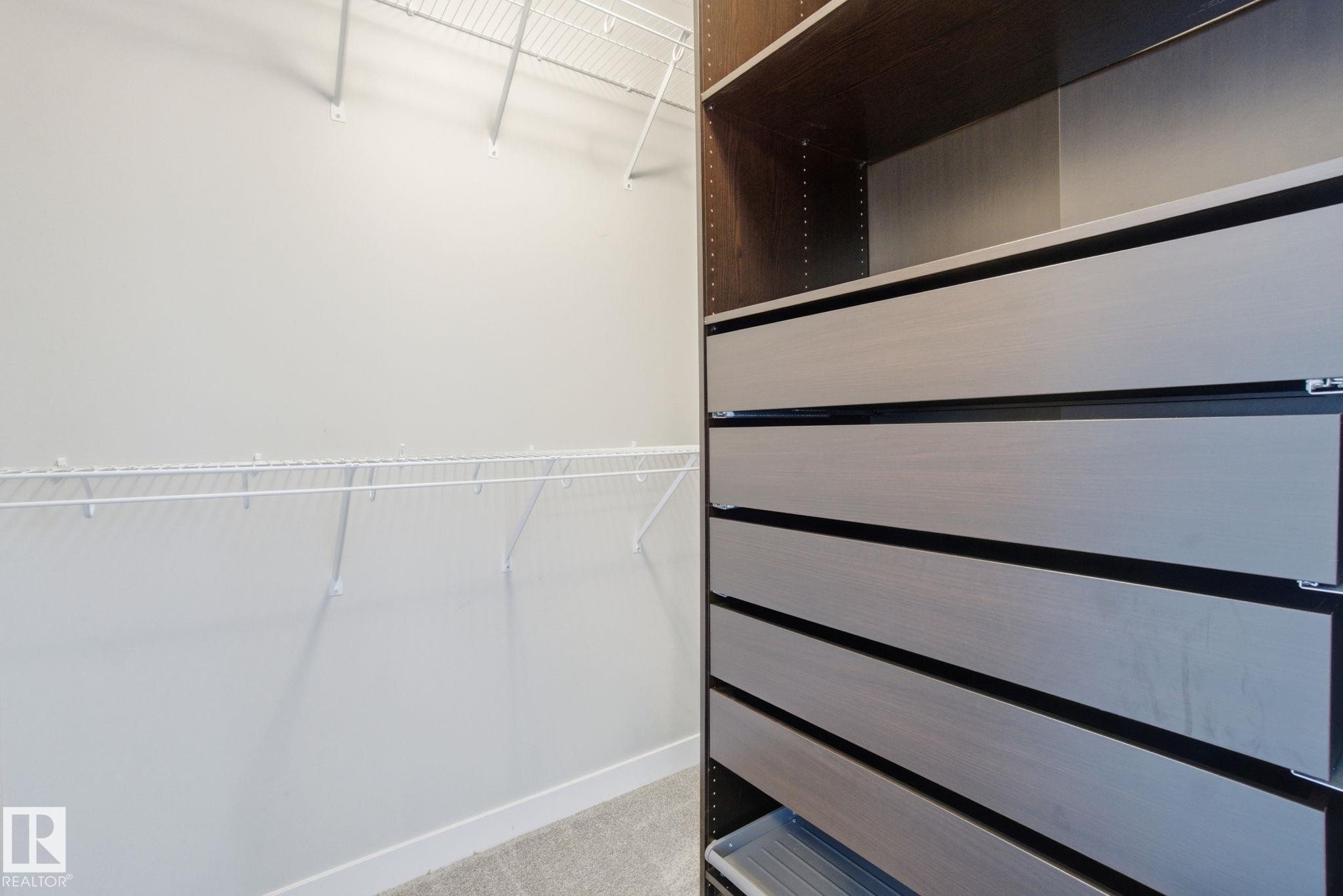 Spacious closet with built-in dark wood shelving and drawers, complemented by white wire shelving - 1607 202 Street, Edmonton, AB - Indoor With Storage