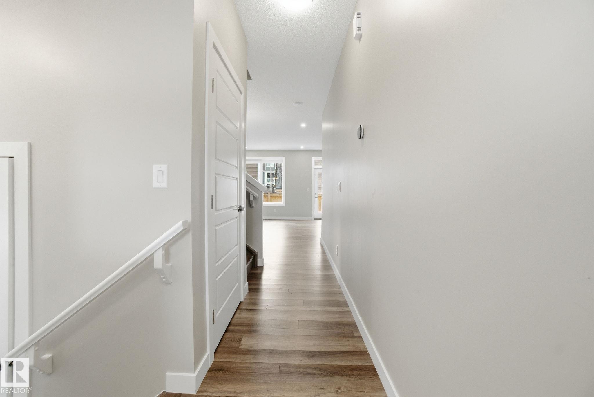 Hallway featuring light-colored walls, wood-style flooring, and white trim - 1607 202 Street, Edmonton, AB - Indoor Photo Showing Other Room