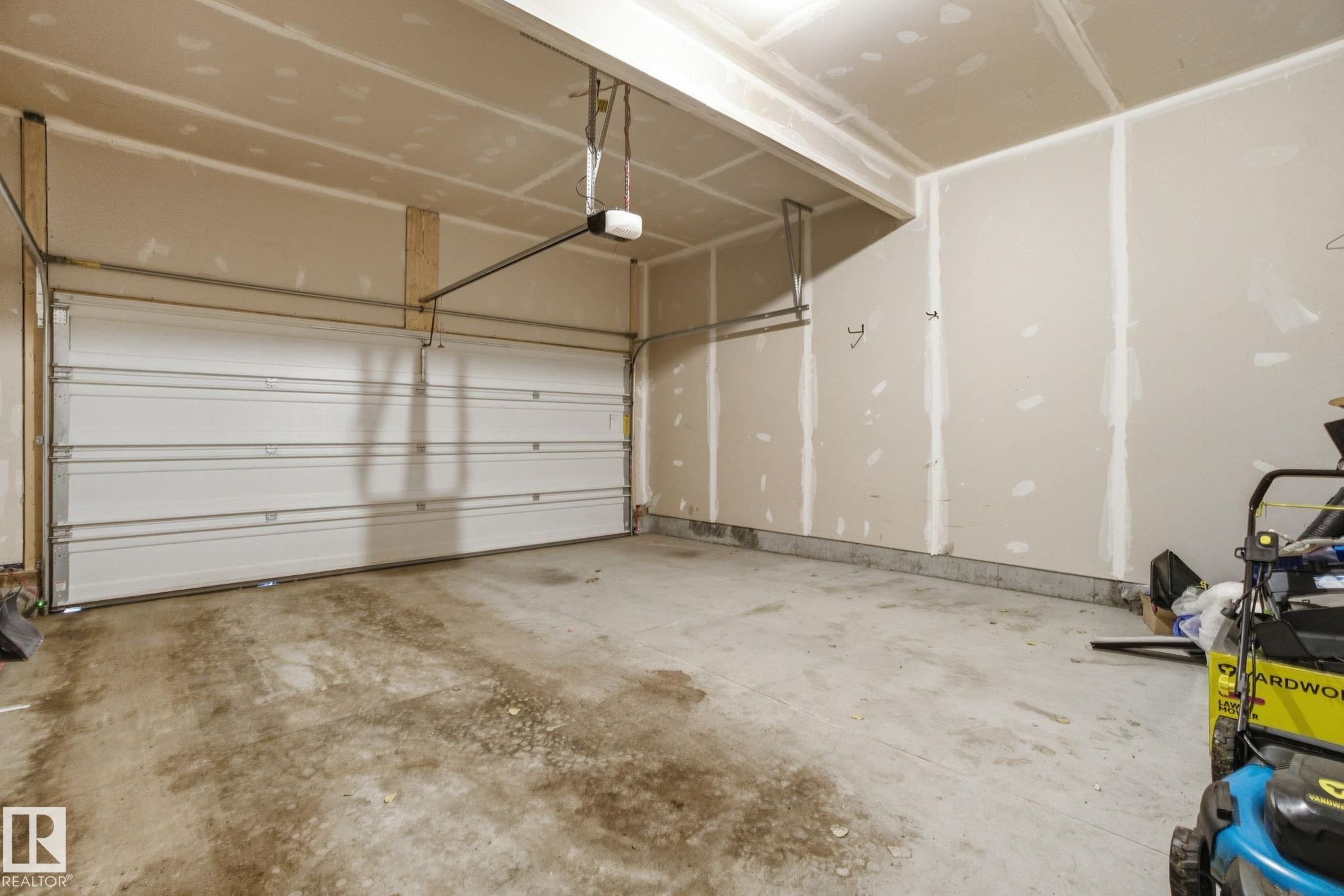 This property features a spacious garage with a white sectional door and a concrete floor - 1607 202 Street, Edmonton, AB - Indoor Photo Showing Garage
