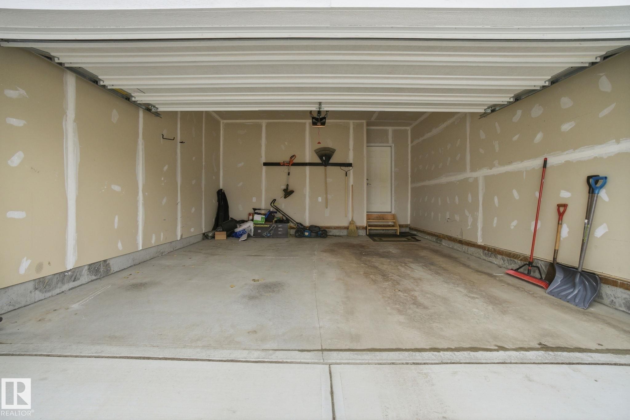 The property includes an attached garage with a concrete floor and a white overhead garage door - 1607 202 Street, Edmonton, AB - Indoor Photo Showing Garage