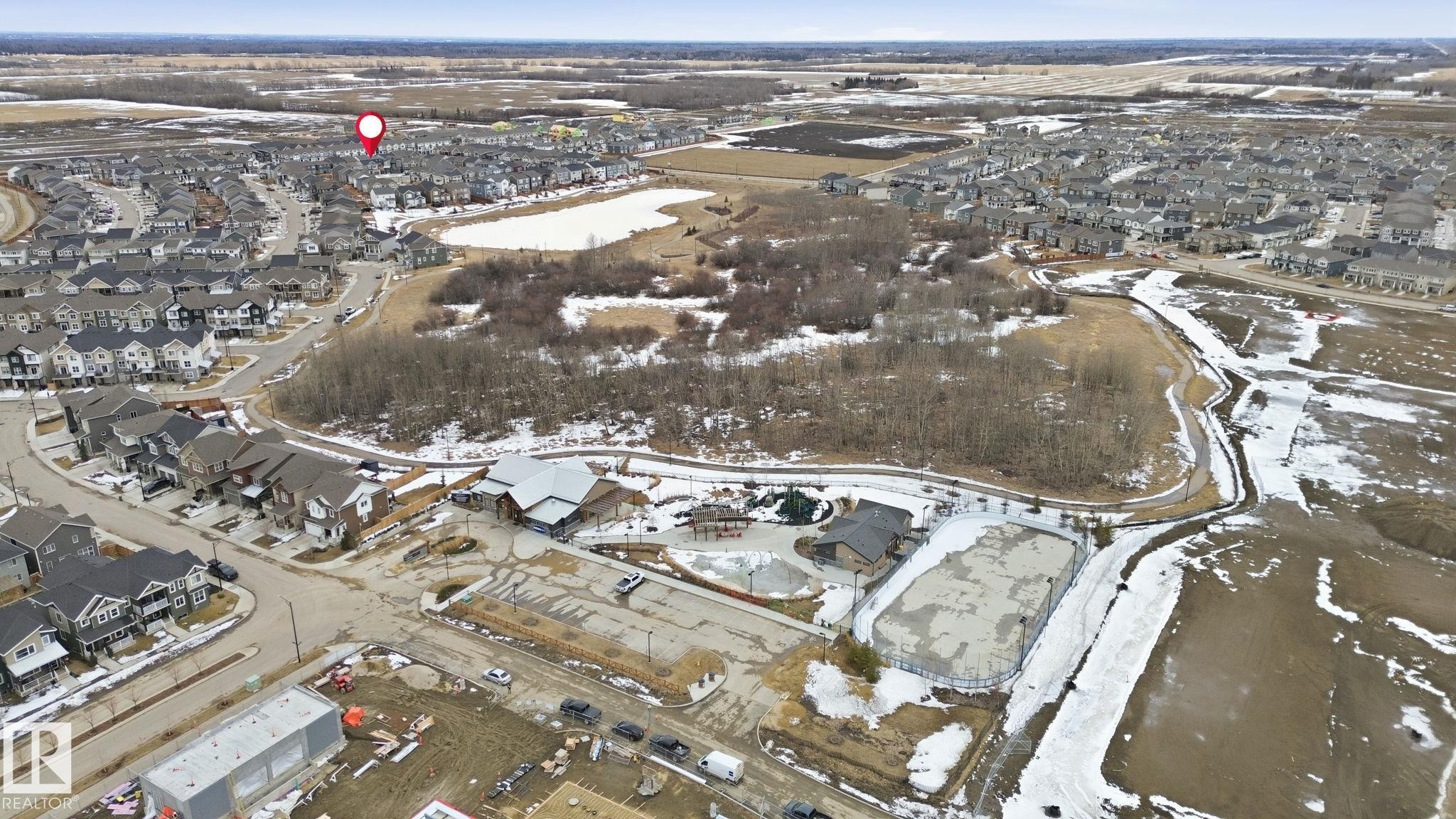 Aerial view highlighting the surrounding community, including residential homes, natural areas with trees, and a pond - 1607 202 Street, Edmonton, AB - Outdoor With View
