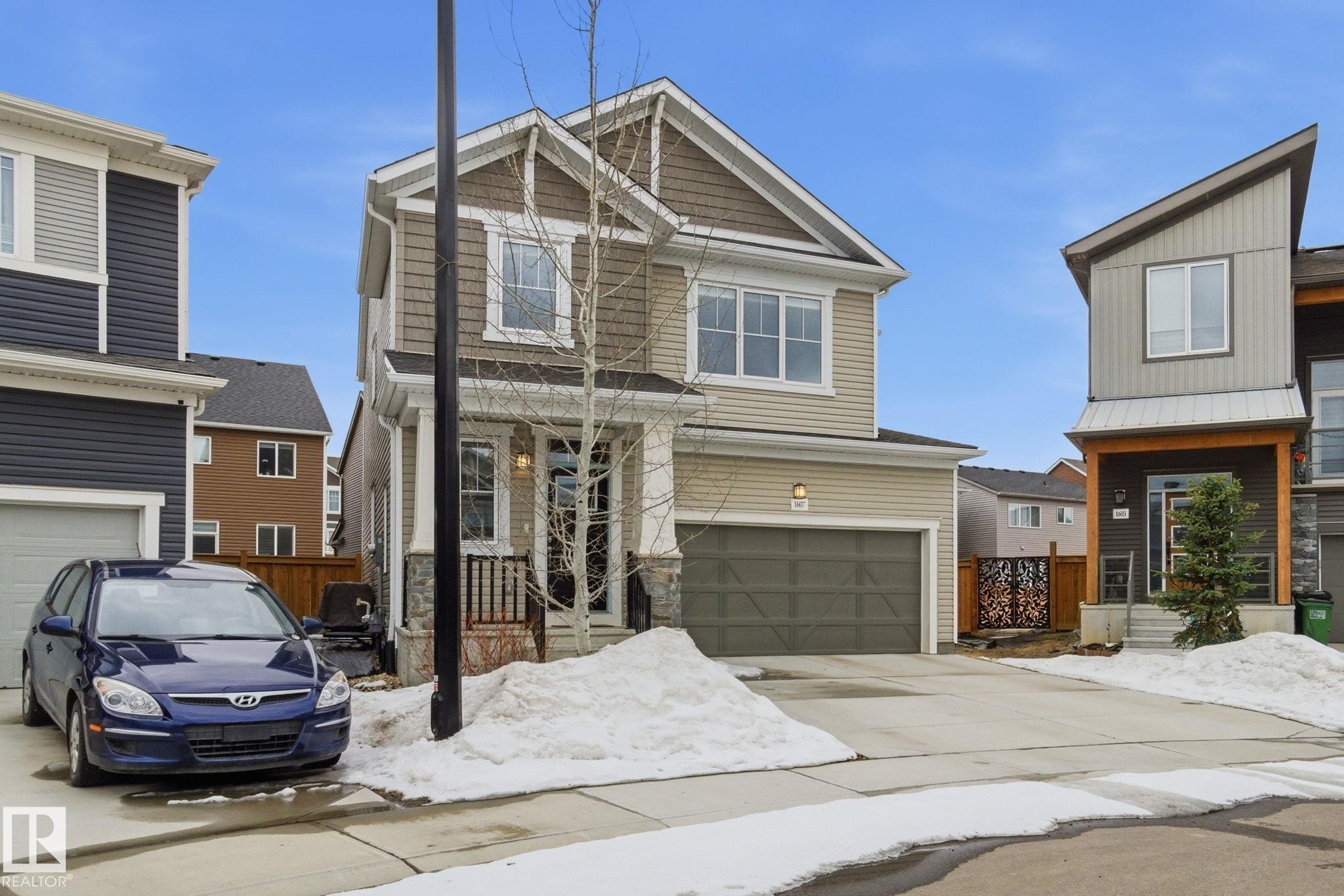 The property features a two-story exterior with siding and stone accents, a front porch, and an attached single-car garage - 1607 202 Street, Edmonton, AB - Outdoor With Facade