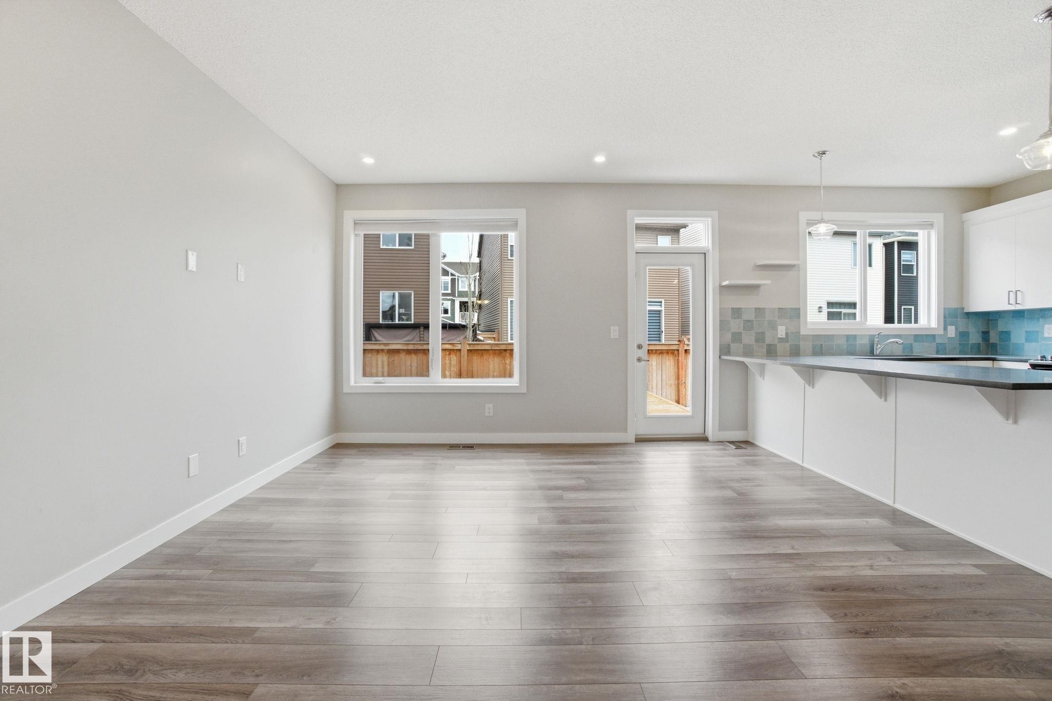 Spacious open concept room featuring light-colored flooring, recessed lighting, and large windows providing natural illumination - 1607 202 Street, Edmonton, AB - Indoor