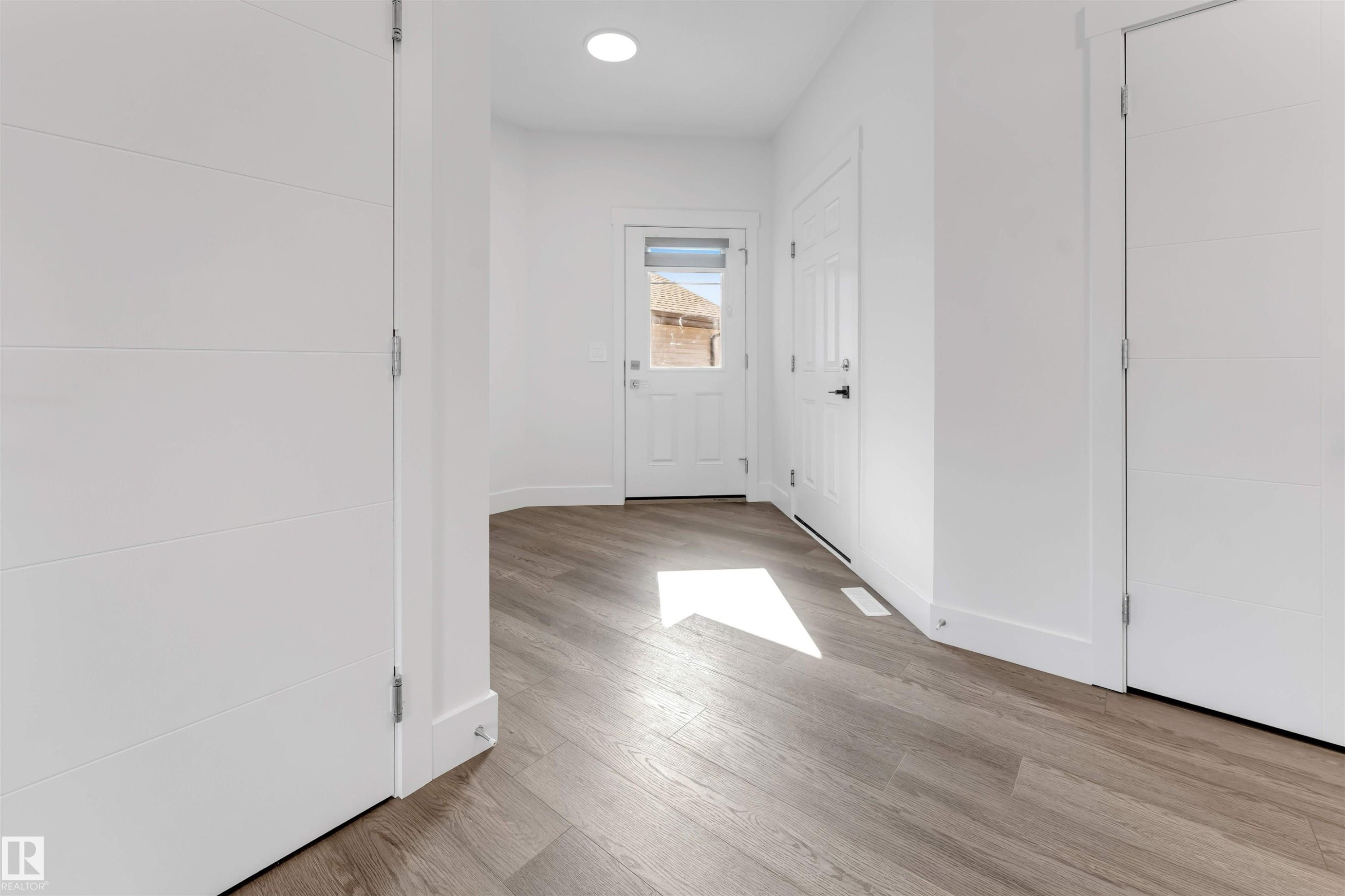 Entryway featuring light wood-look flooring, white walls, and a modern ceiling light fixture - 1663 Cavanagh Boulevard Sw, Edmonton, AB - Indoor Photo Showing Other Room