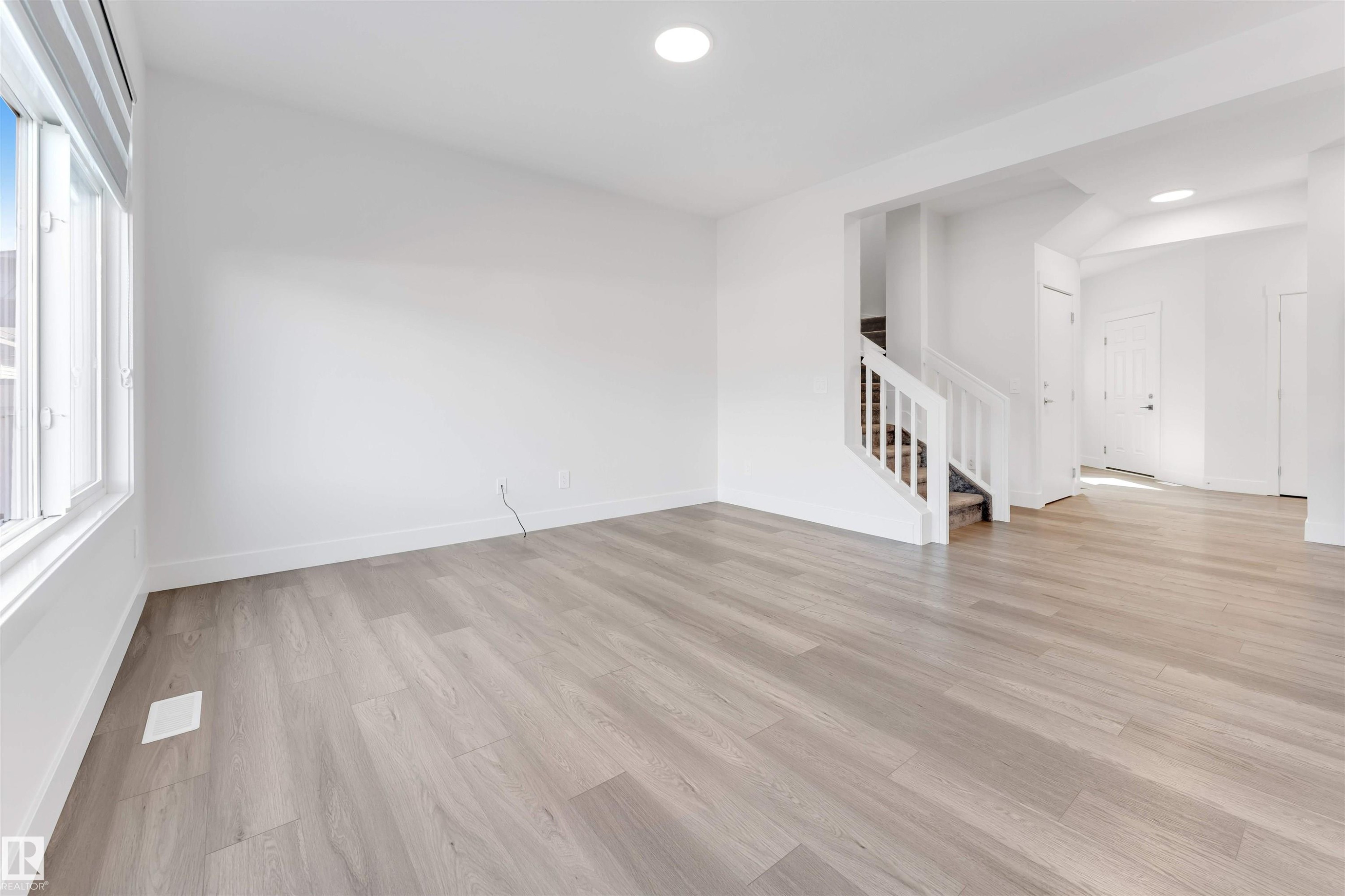 Bright living area with light-colored flooring, white walls, and a large window - 1663 Cavanagh Boulevard Sw, Edmonton, AB - Indoor Photo Showing Other Room