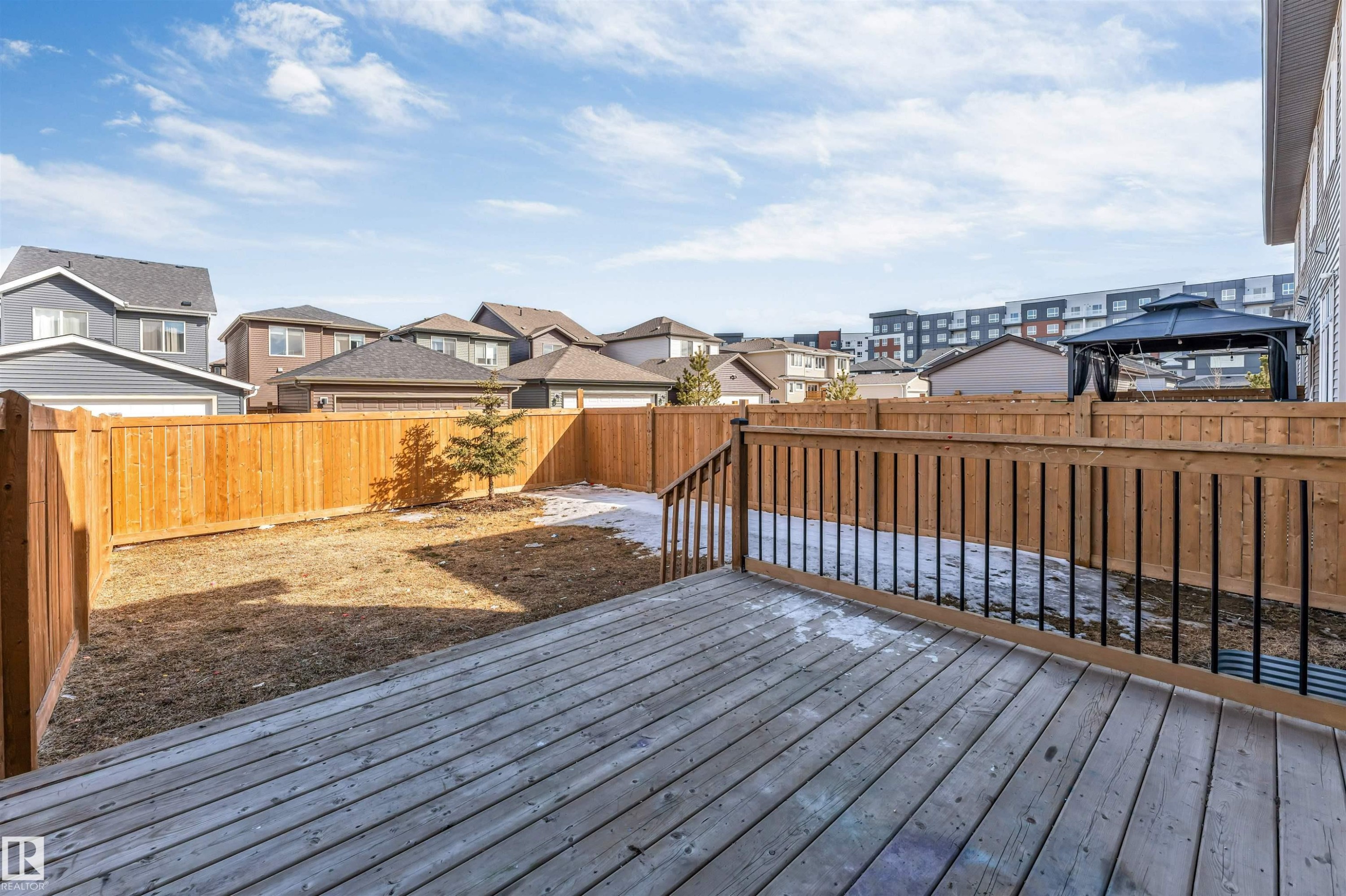 The property features a spacious wooden deck with railings, overlooking a fenced yard - 1663 Cavanagh Boulevard Sw, Edmonton, AB - Outdoor