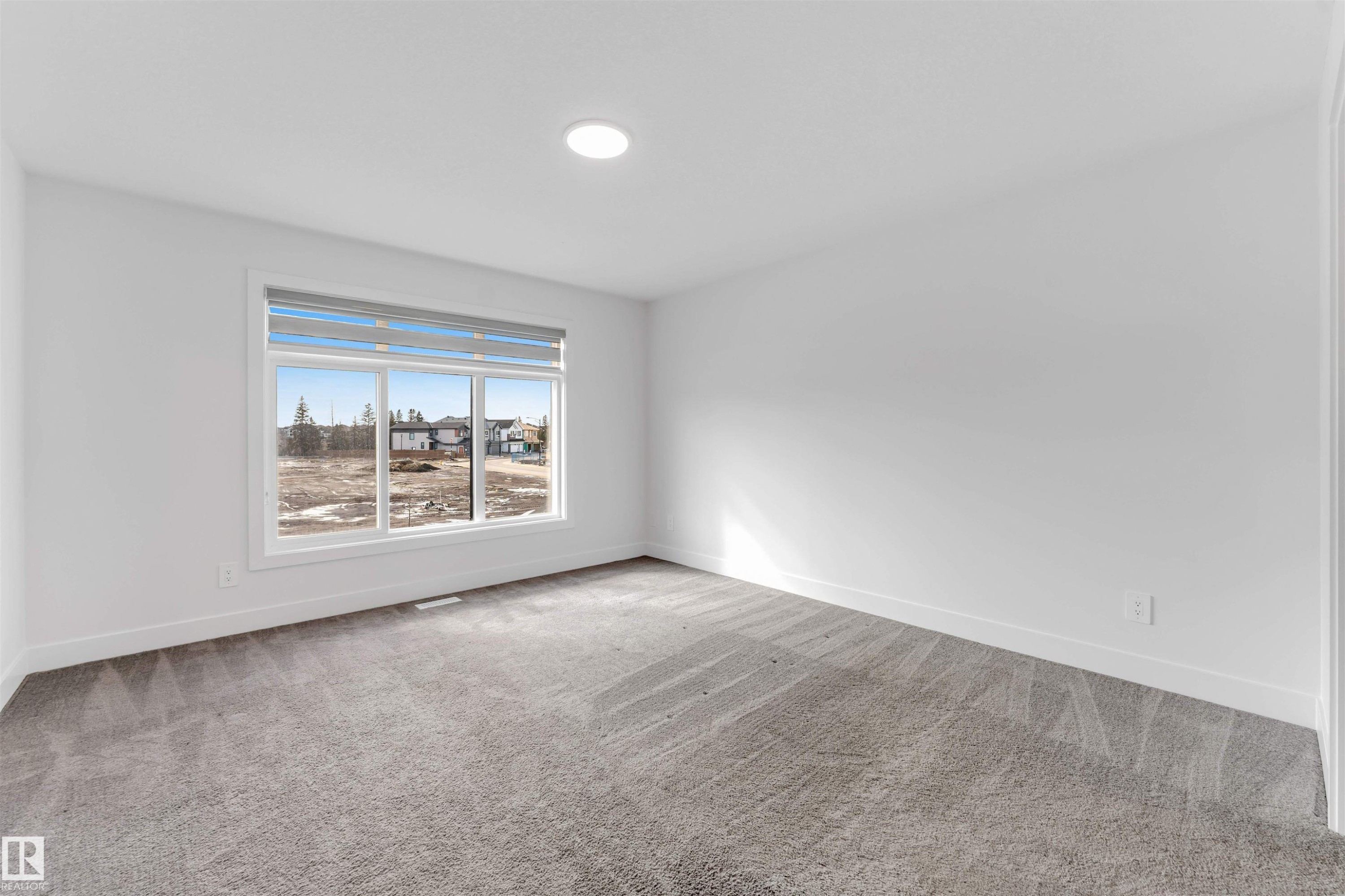 This room features neutral grey carpeting and a large window with horizontal blinds, providing ample natural light - 1663 Cavanagh Boulevard Sw, Edmonton, AB - Indoor Photo Showing Other Room