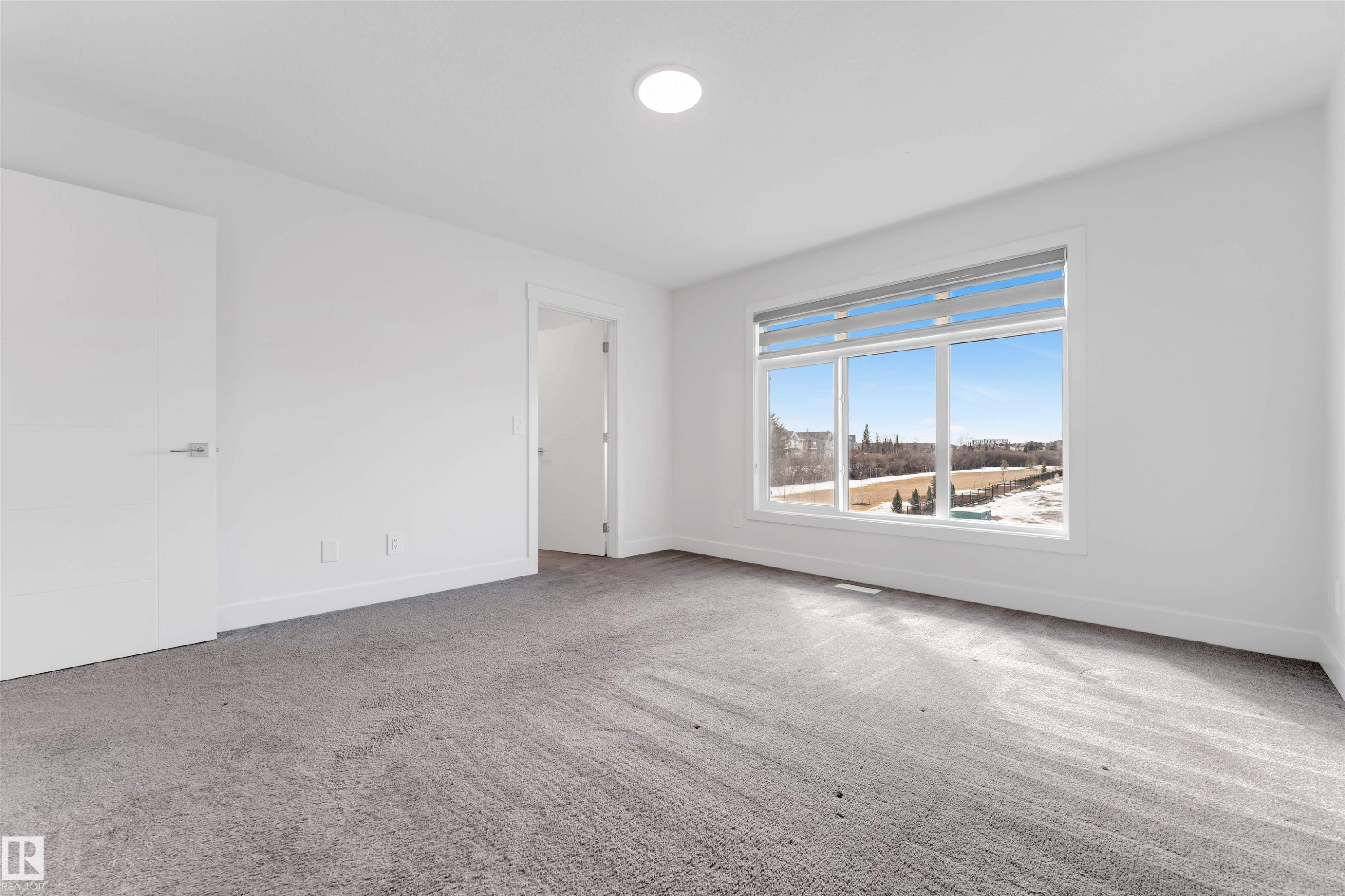 This room features light gray carpeting, white walls, and a large window with horizontal blinds - 1663 Cavanagh Boulevard Sw, Edmonton, AB - Indoor Photo Showing Other Room