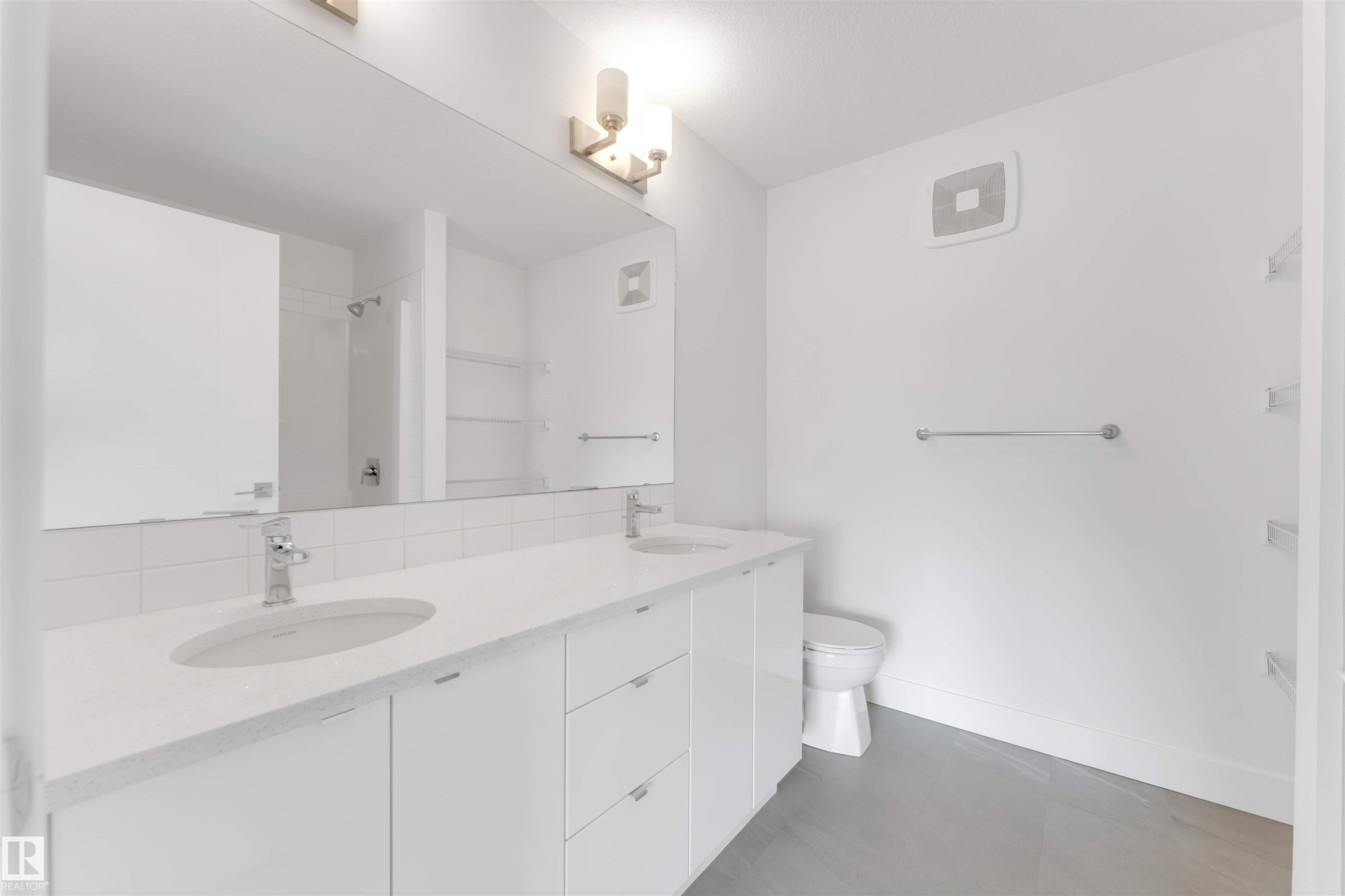 This bathroom features a double vanity with two sinks and a spacious mirror - 1663 Cavanagh Boulevard Sw, Edmonton, AB - Indoor Photo Showing Bathroom