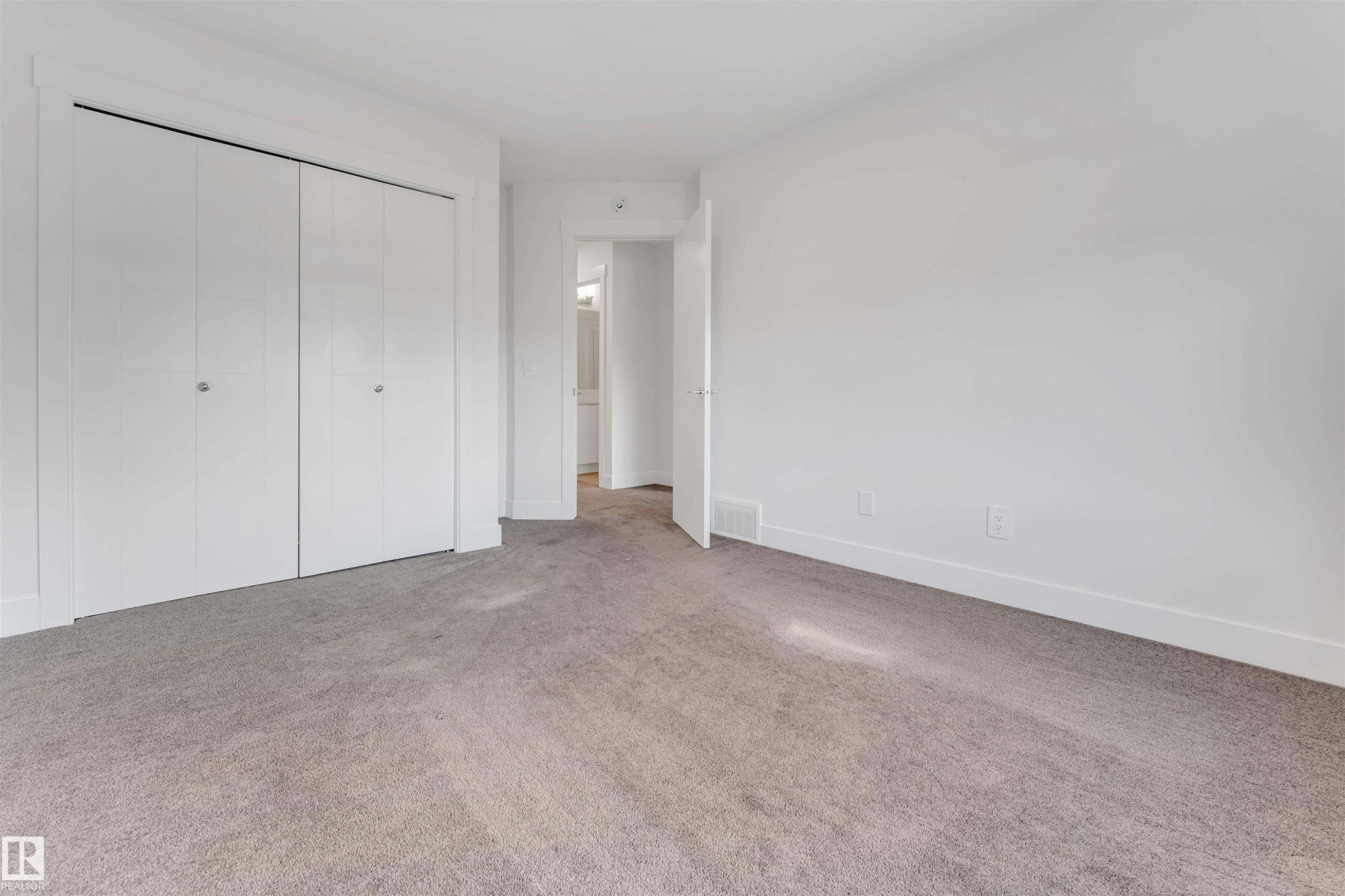 This room features light gray carpeting, white walls, and white bi-fold closet doors - 1663 Cavanagh Boulevard Sw, Edmonton, AB - Indoor Photo Showing Other Room