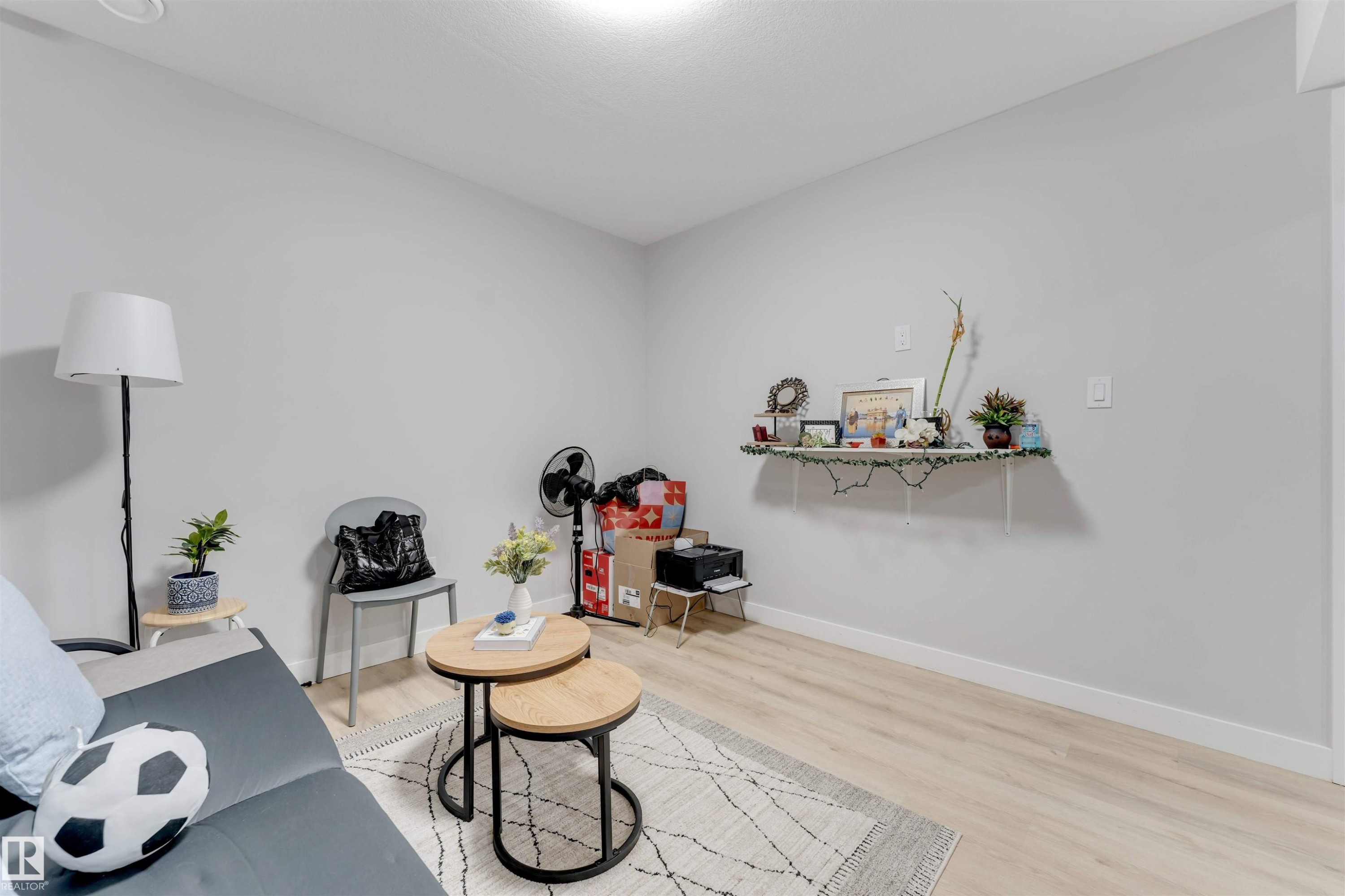 This room features light-colored walls, light wood flooring, and a decorative wall shelf - 1663 Cavanagh Boulevard Sw, Edmonton, AB - Indoor Photo Showing Other Room