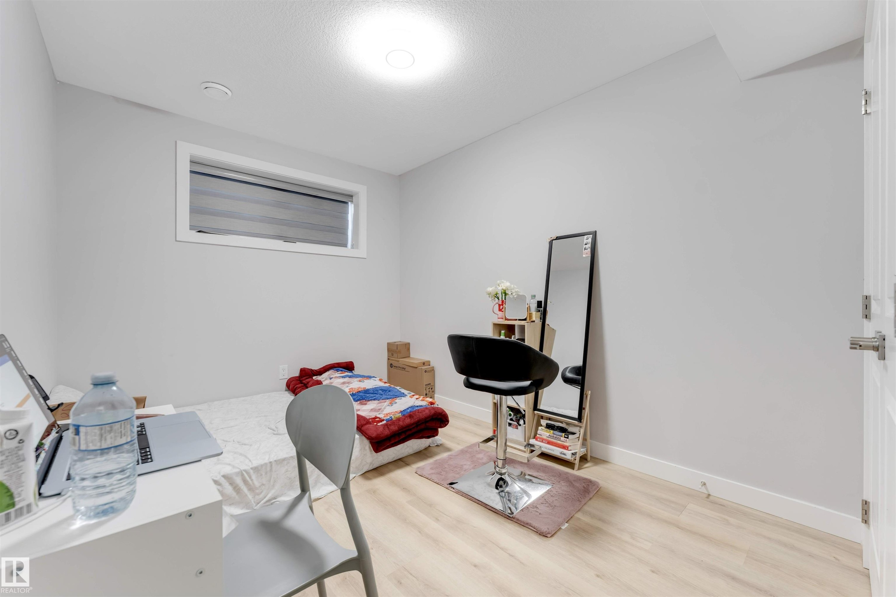 This room features light-colored walls, light wood-style flooring, and a single window with blinds - 1663 Cavanagh Boulevard Sw, Edmonton, AB - Indoor