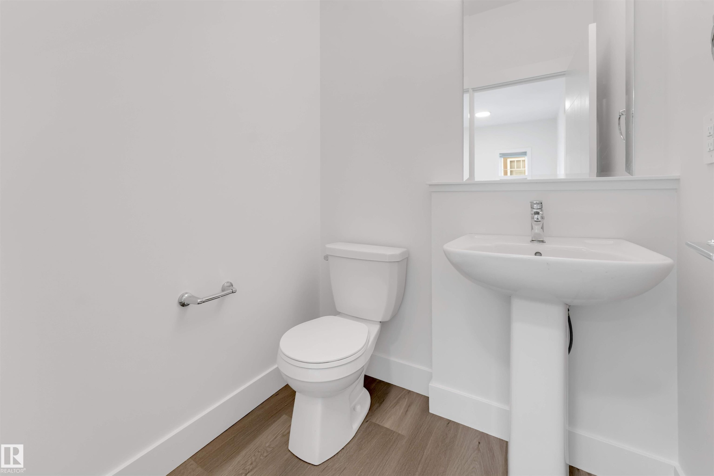 A clean, modern bathroom with a white pedestal sink, toilet, and light wood-style flooring - 1663 Cavanagh Boulevard Sw, Edmonton, AB - Indoor Photo Showing Bathroom
