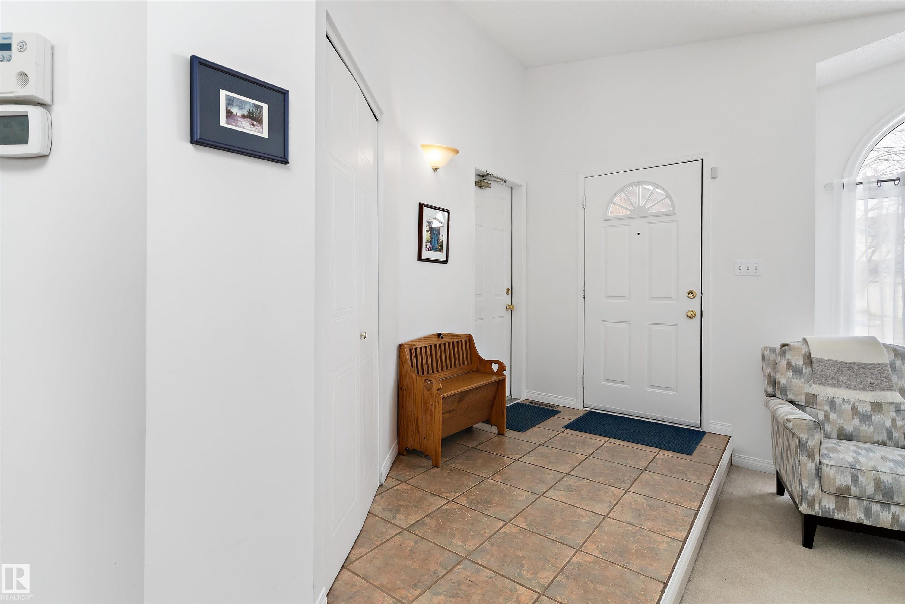The entry features a white front door with an arched window, tile flooring, and a closet with bifold doors - 322 Pearson Crescent, Edmonton, AB - Indoor Photo Showing Other Room