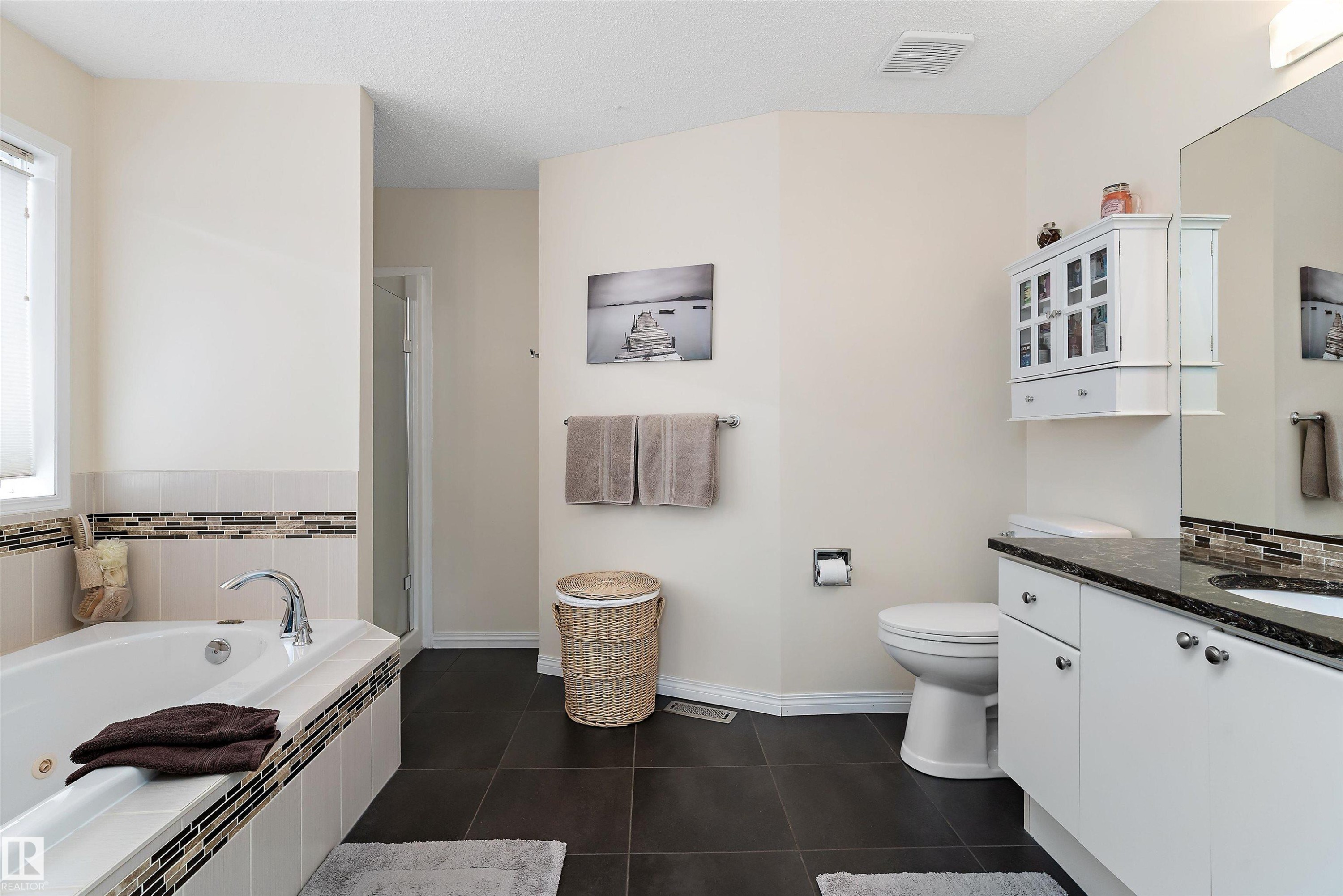 Bathroom featuring a built-in bathtub with tiled surround, a separate shower enclosure, and a vanity with a dark countertop and white cabinetry - 322 Pearson Crescent, Edmonton, AB - Indoor Photo Showing Bathroom