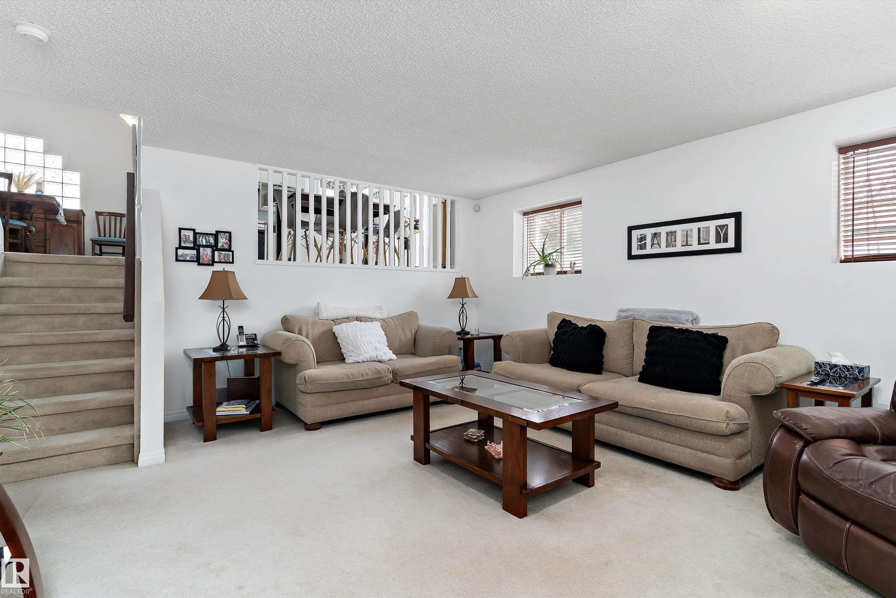 Spacious living area featuring light-colored carpet, white walls, and stairs with carpeted treads - 322 Pearson Crescent, Edmonton, AB - Indoor Photo Showing Living Room