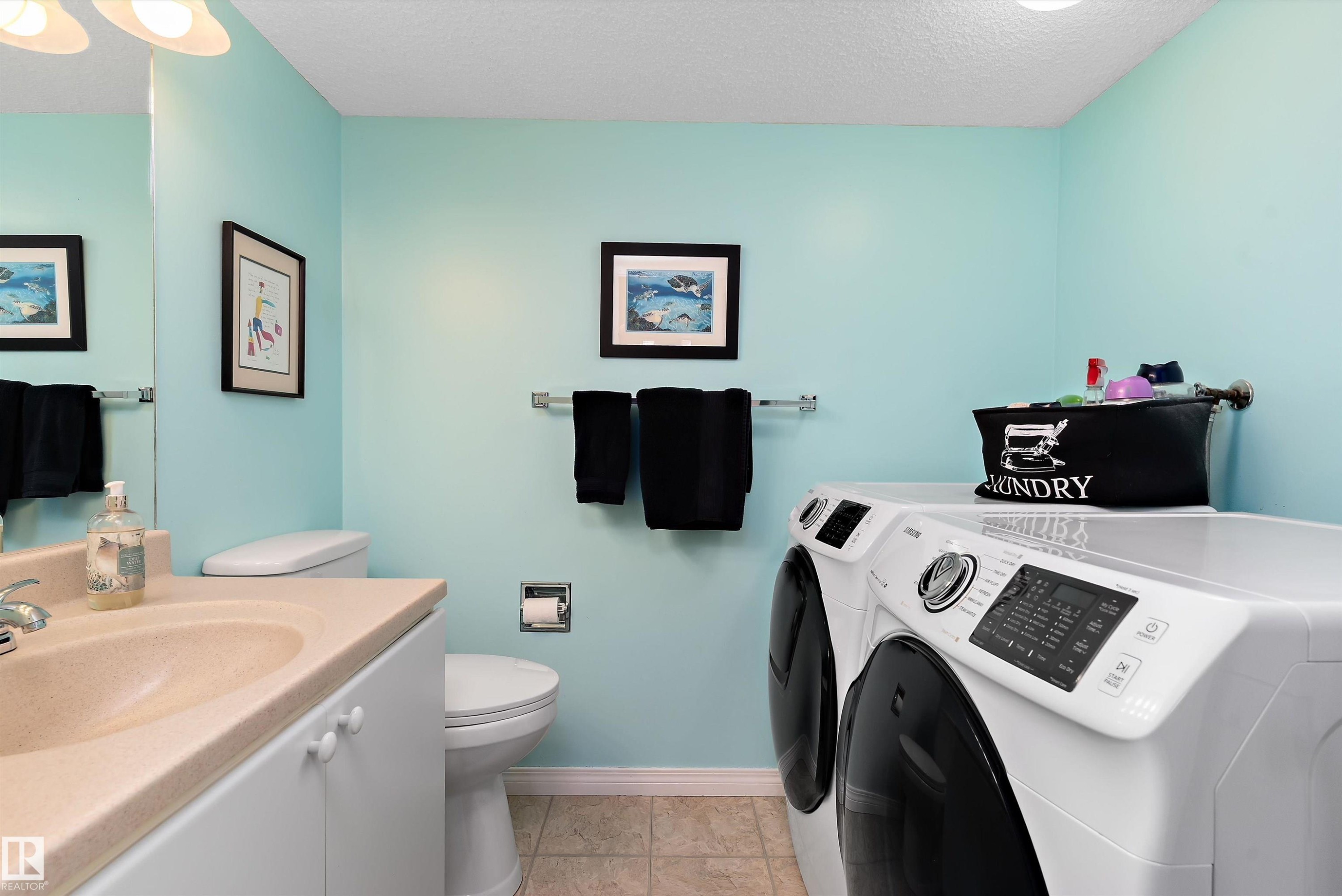 This room features a vanity with an integrated sink, a toilet, a washer, and a dryer - 322 Pearson Crescent, Edmonton, AB - Indoor Photo Showing Laundry Room