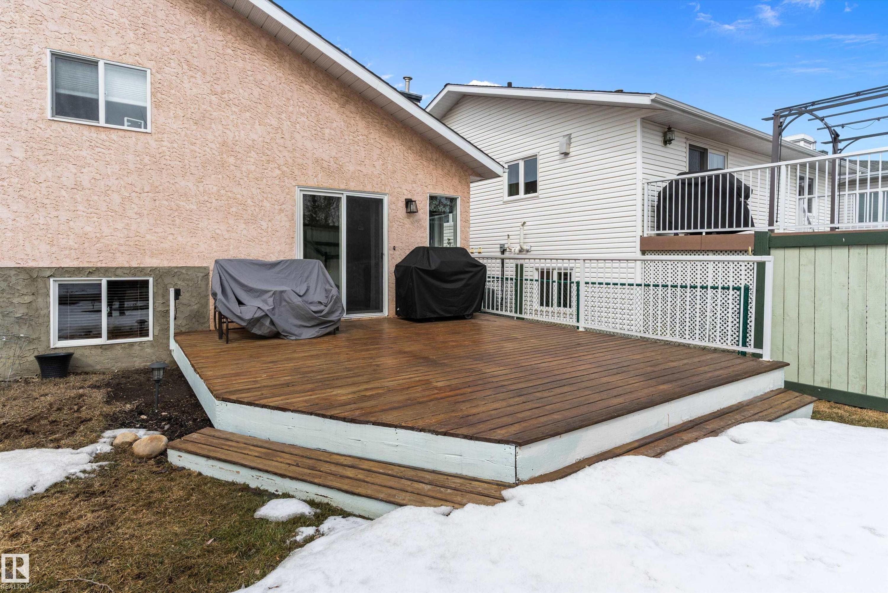 The property features a spacious wooden deck with white railing, accessible via a sliding glass door, providing an inviting outdoor area - 322 Pearson Crescent, Edmonton, AB - Outdoor With Exterior