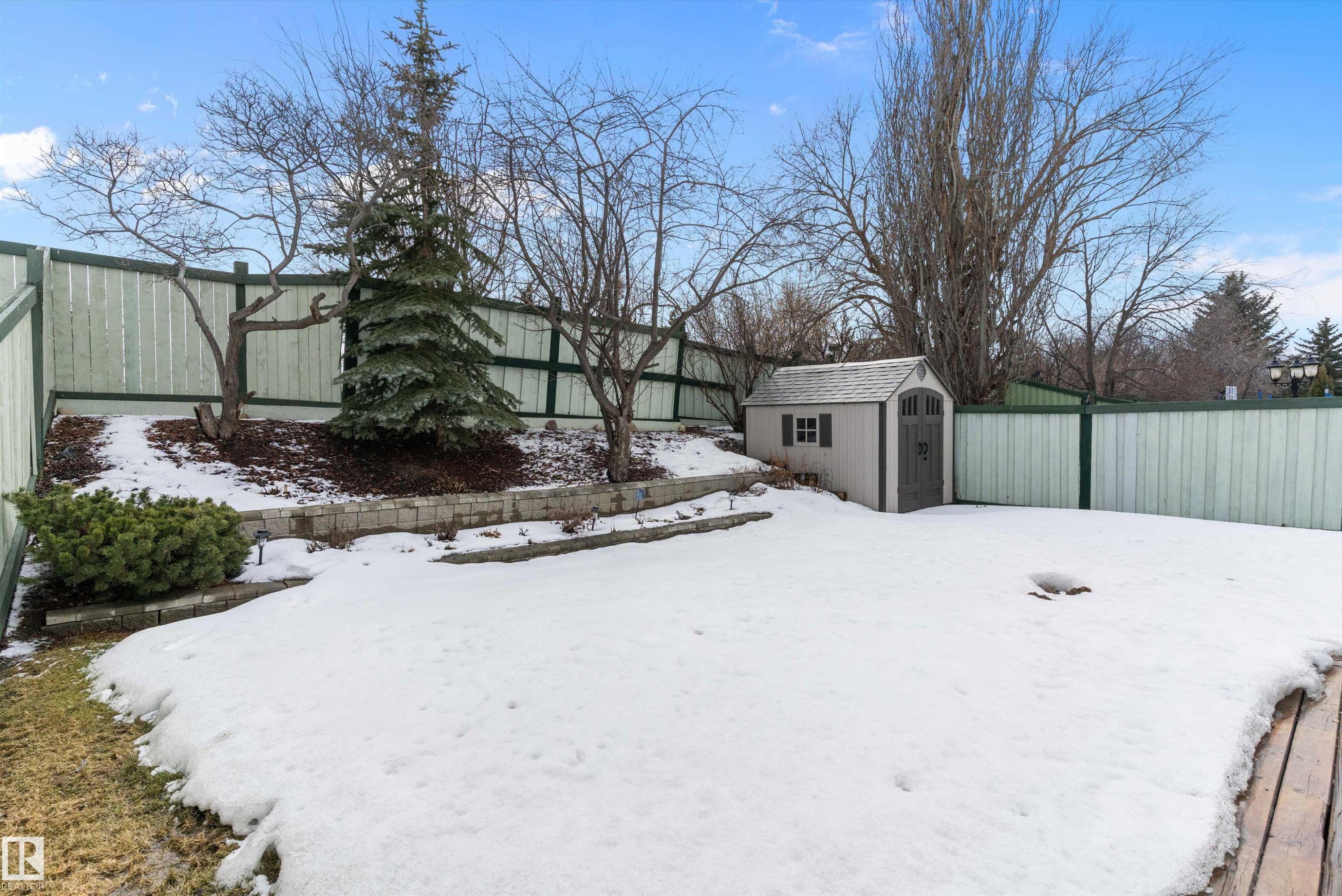 The property features a fenced yard with a small shed, mature trees, and a retaining wall - 322 Pearson Crescent, Edmonton, AB - Outdoor