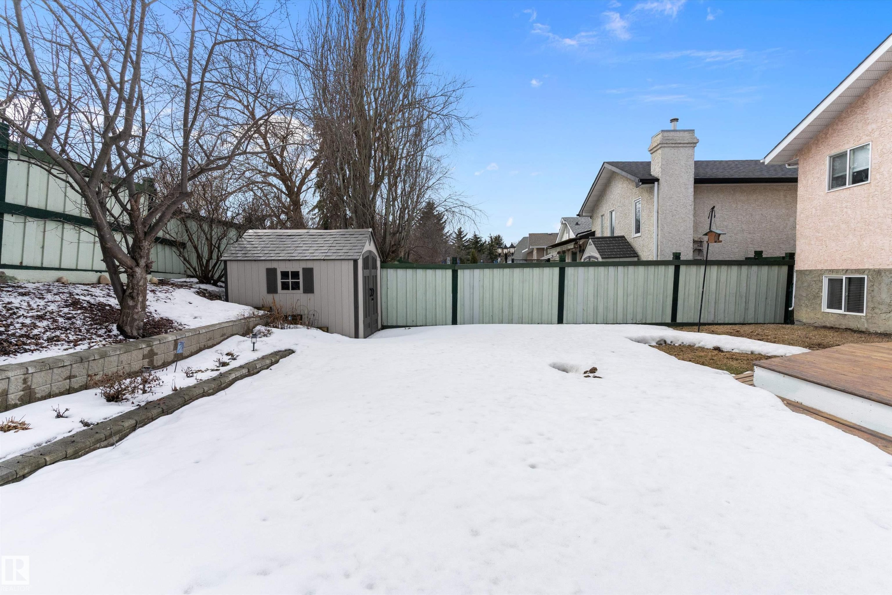 The property features a spacious yard with a storage shed, a retaining wall, and a wooden deck area - 322 Pearson Crescent, Edmonton, AB - Outdoor