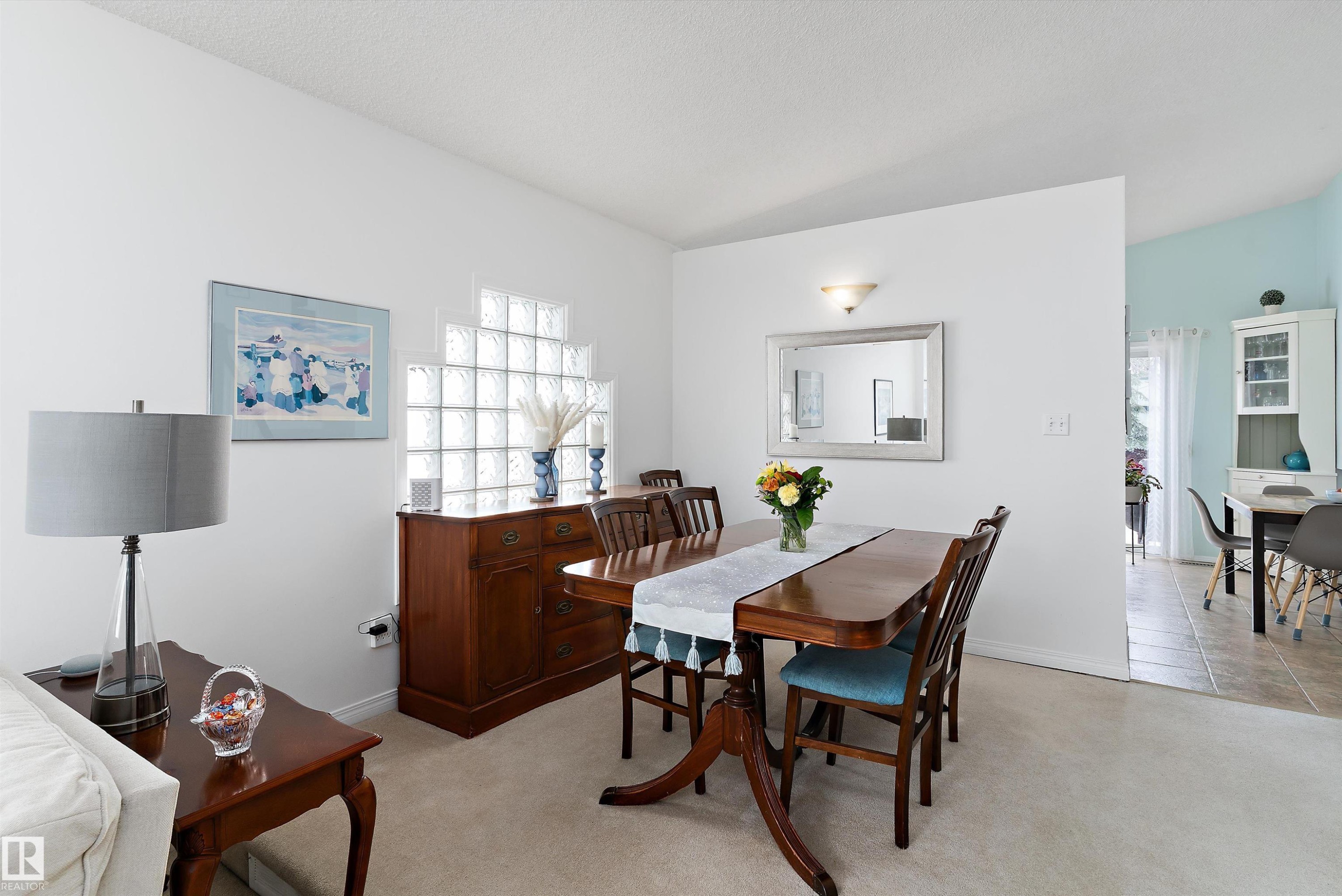 The property features an open-concept dining area with a hardwood table, matching chairs, and carpeted flooring - 322 Pearson Crescent, Edmonton, AB - Indoor Photo Showing Dining Room