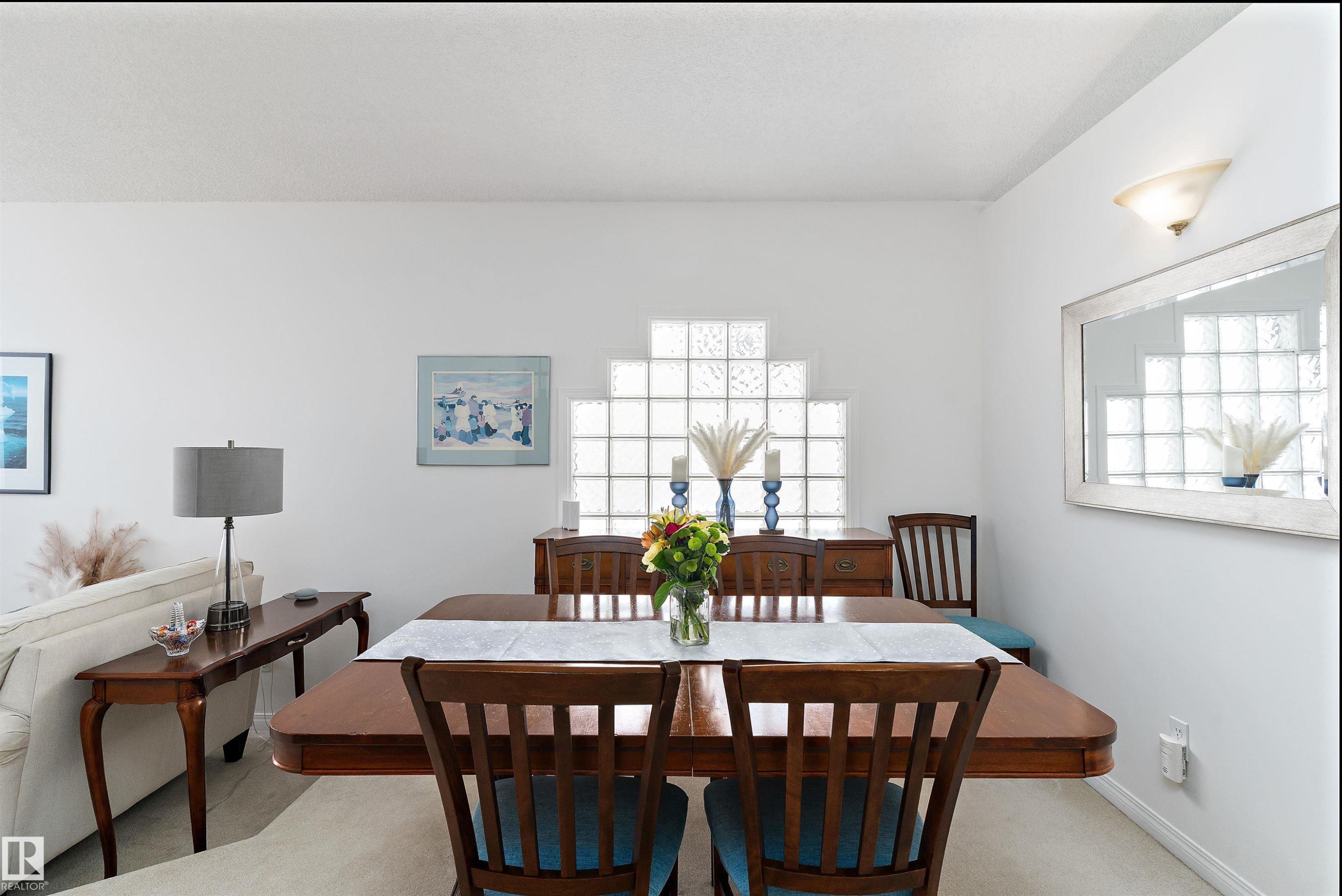 The dining area features a wooden dining table and chairs, a glass block window, and light-colored walls - 322 Pearson Crescent, Edmonton, AB - Indoor Photo Showing Dining Room