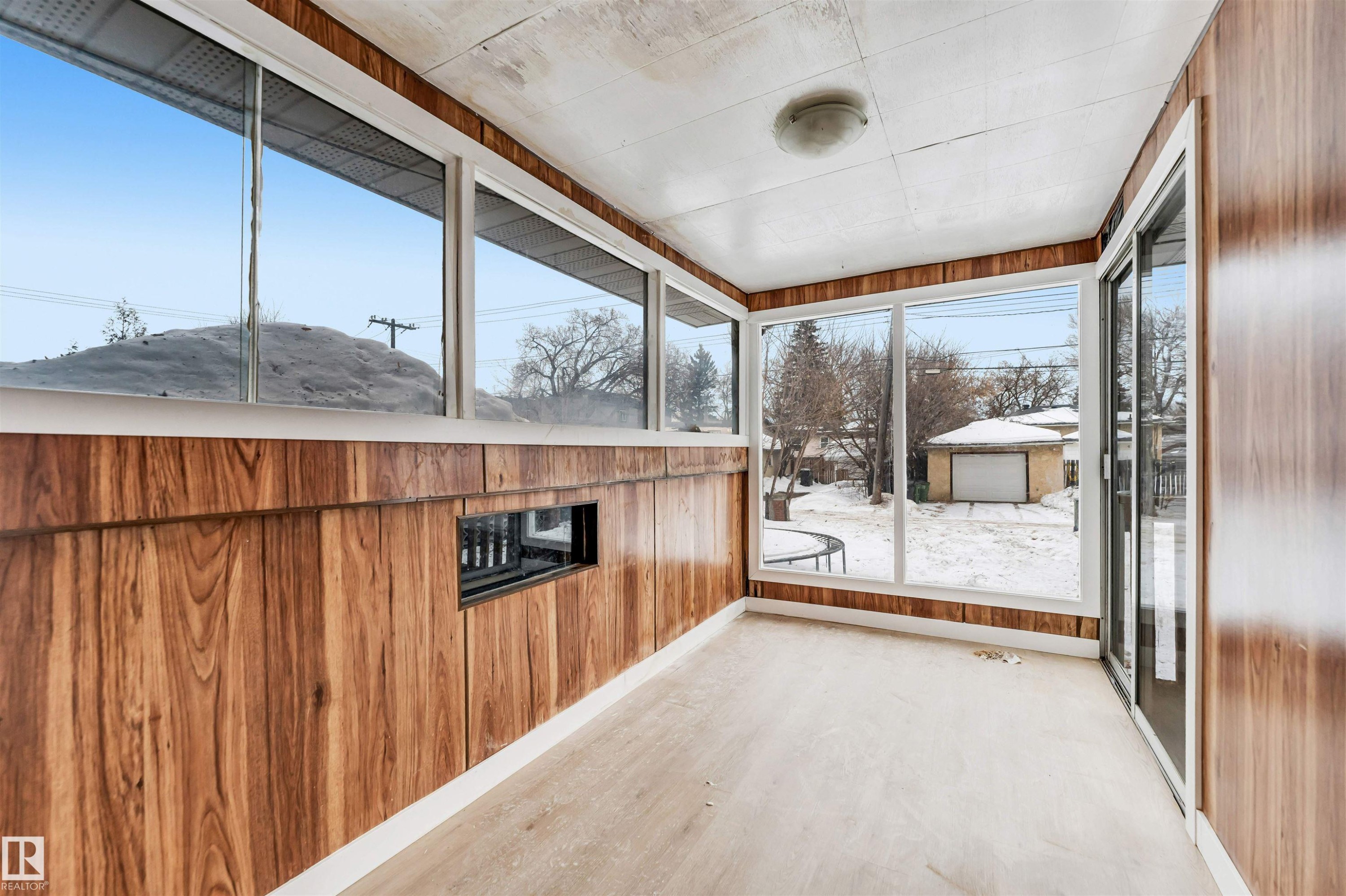 The property features a sunroom with extensive windows, wood paneling, and a light-colored floor - 12423 91 Street, Edmonton, AB - With Exterior