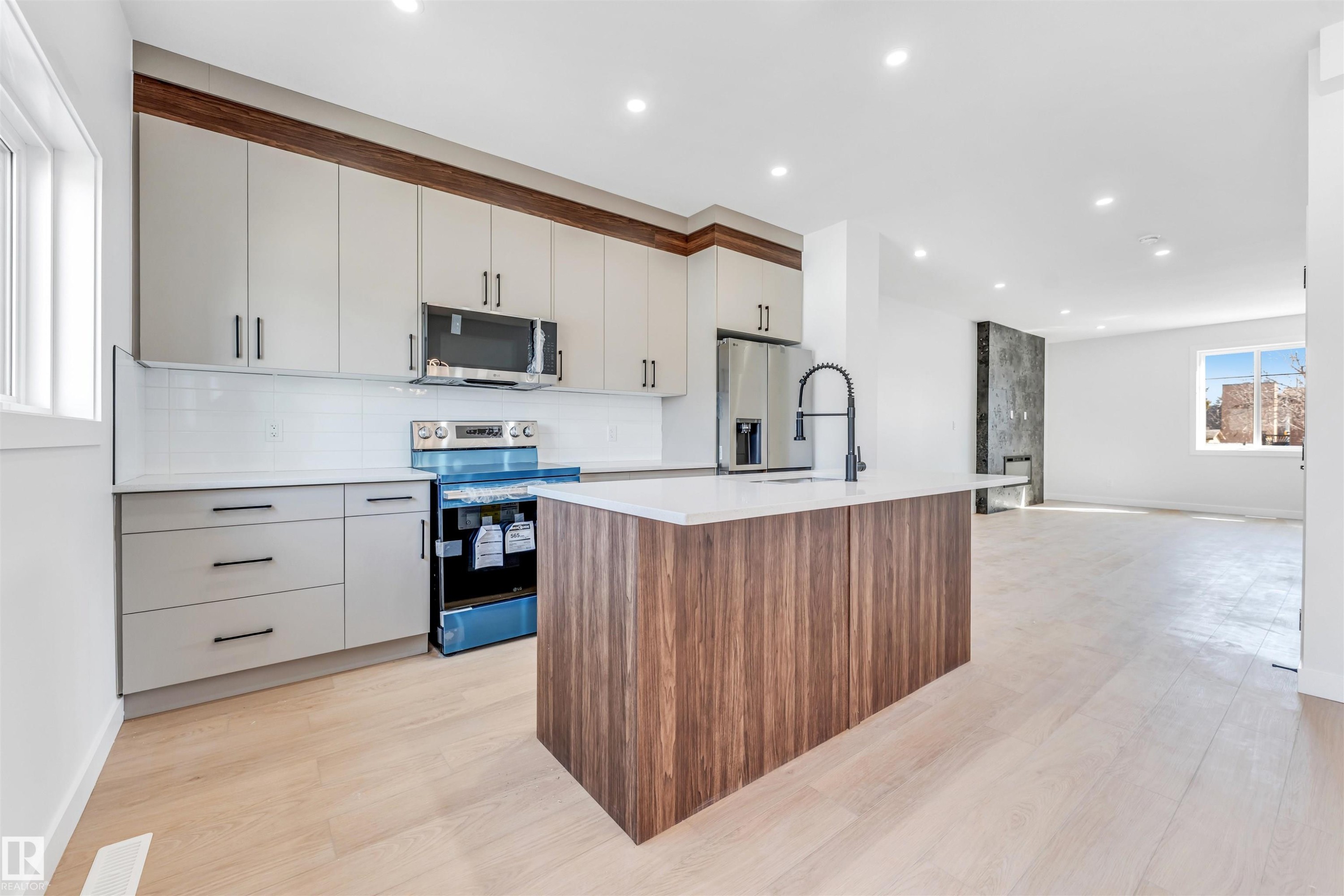 The kitchen features light-colored cabinetry with dark hardware, a white subway tile backsplash, and stainless steel appliances - 10962 157 Street, Edmonton, AB - Indoor Photo Showing Kitchen With Upgraded Kitchen