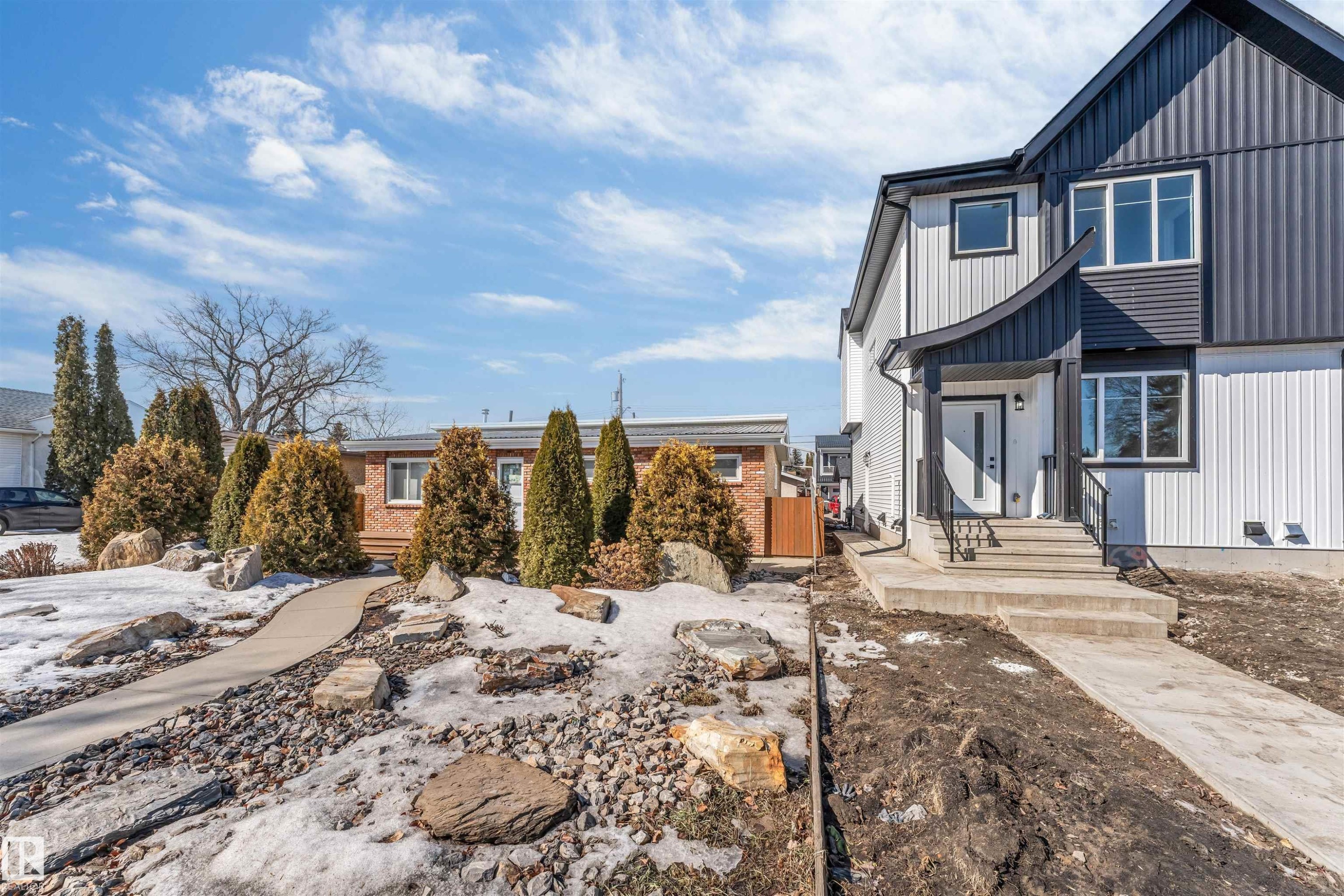 The property features a modern exterior with a white and dark grey facade, a covered front entrance, and concrete steps leading to the front door - 10962 157 Street, Edmonton, AB - Outdoor