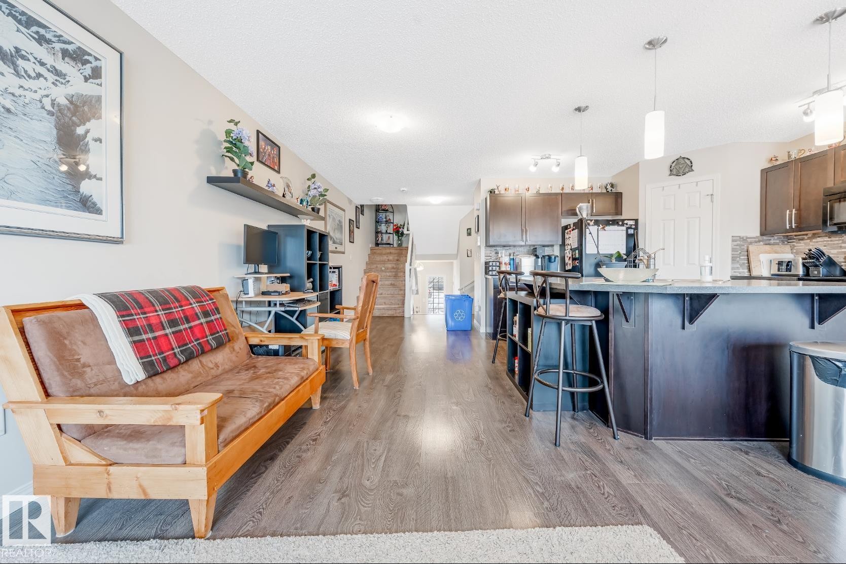 The main living area features durable flooring, a well-appointed kitchen with dark cabinetry, and a breakfast bar with seating - 3109 Carpenter Landing, Edmonton, AB - Indoor Photo Showing Kitchen With Upgraded Kitchen