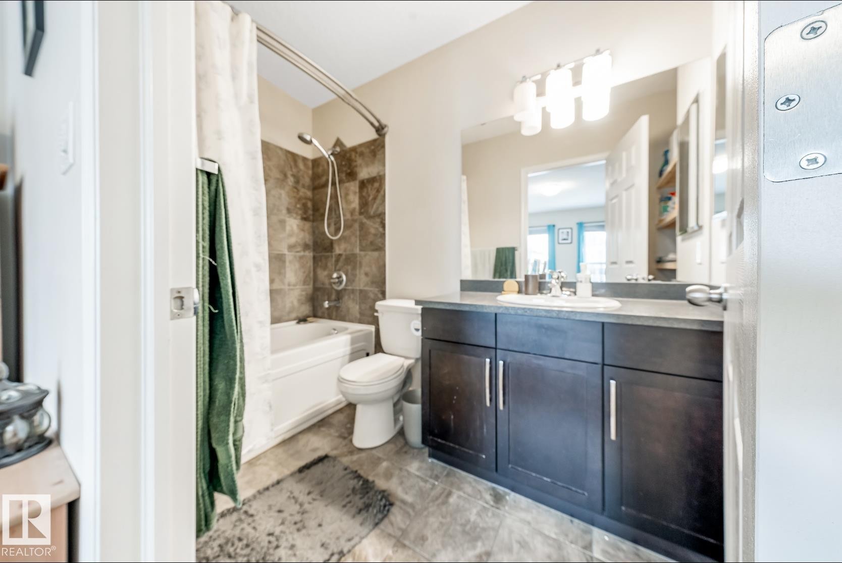 The bathroom features a vanity with a dark wood finish and a white sink, a bathtub with a shower, and tiled walls - 3109 Carpenter Landing, Edmonton, AB - Indoor Photo Showing Bathroom