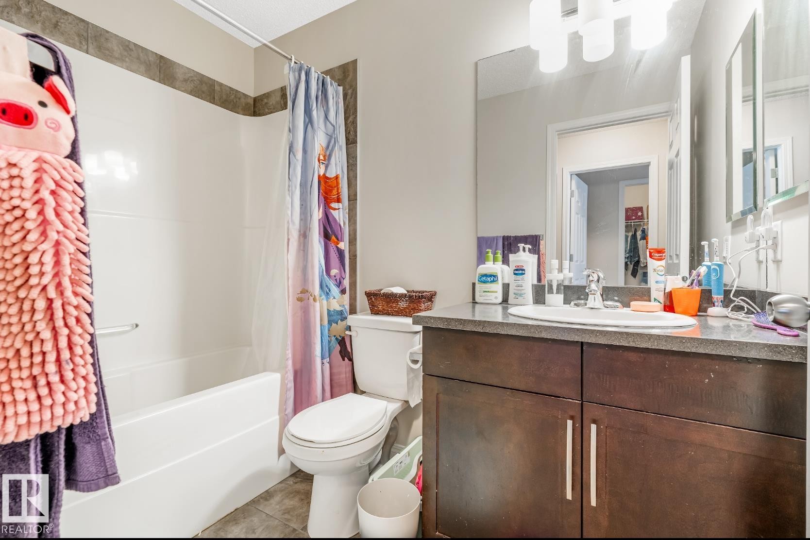 Bathroom featuring a vanity with a dark countertop, an integrated sink, and a large mirror - 3109 Carpenter Landing, Edmonton, AB - Indoor Photo Showing Bathroom