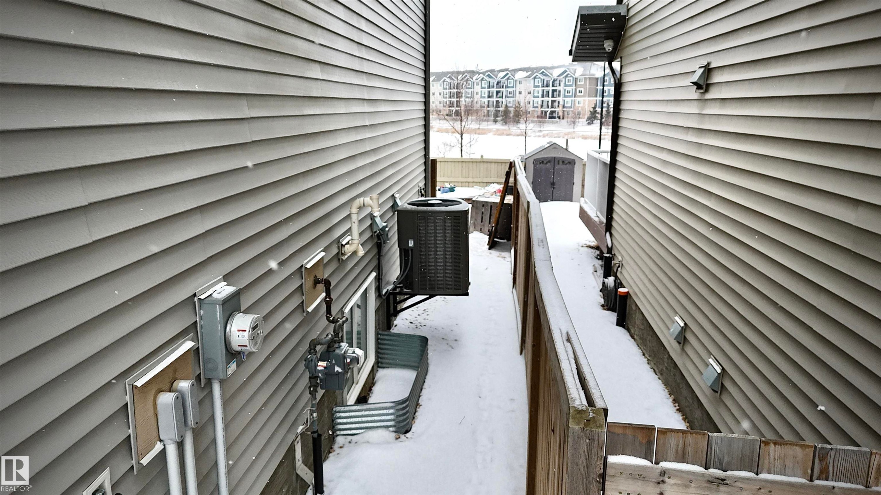 The property features exterior siding, a ground-level window with a window well, and an outdoor HVAC unit - 3109 Carpenter Landing, Edmonton, AB - Outdoor