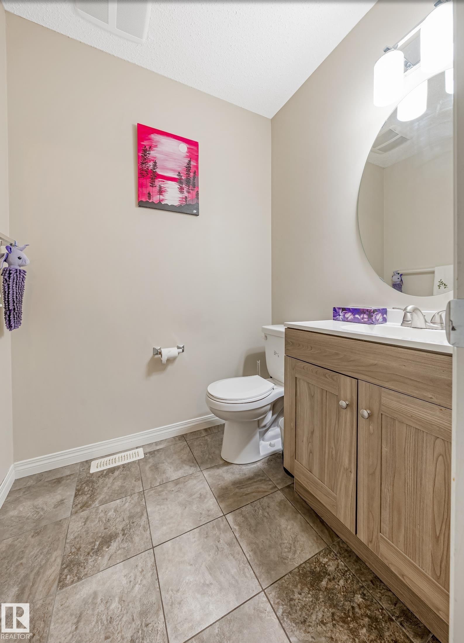 This bathroom features tile flooring, a neutral-toned vanity with cabinet storage, and a round mirror - 3109 Carpenter Landing, Edmonton, AB - Indoor Photo Showing Bathroom