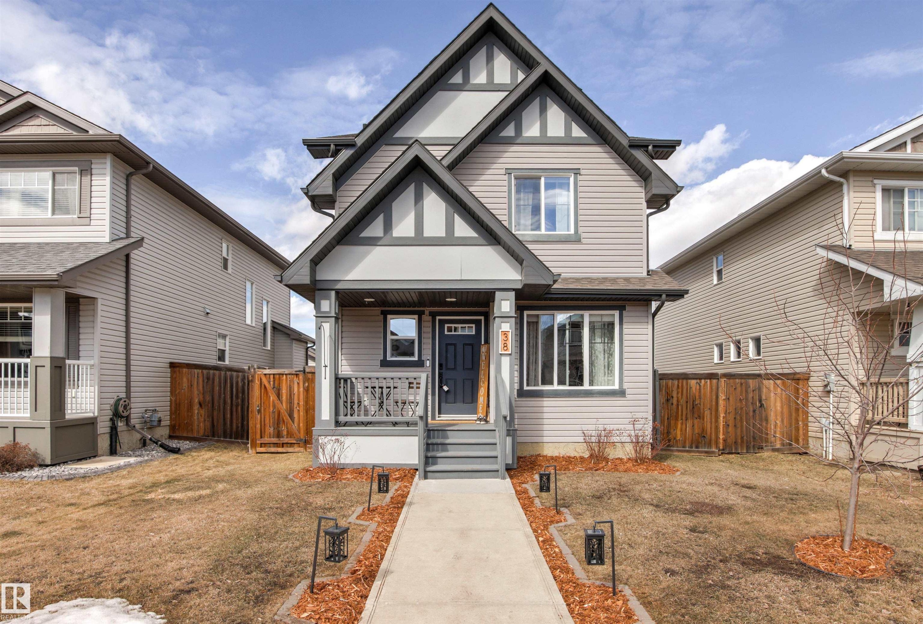 The property features a charming exterior with a covered front porch, a well-defined walkway leading to the entrance, and decorative exterior lighting - 38 Hewitt Circle, Spruce Grove, AB - Outdoor With Facade