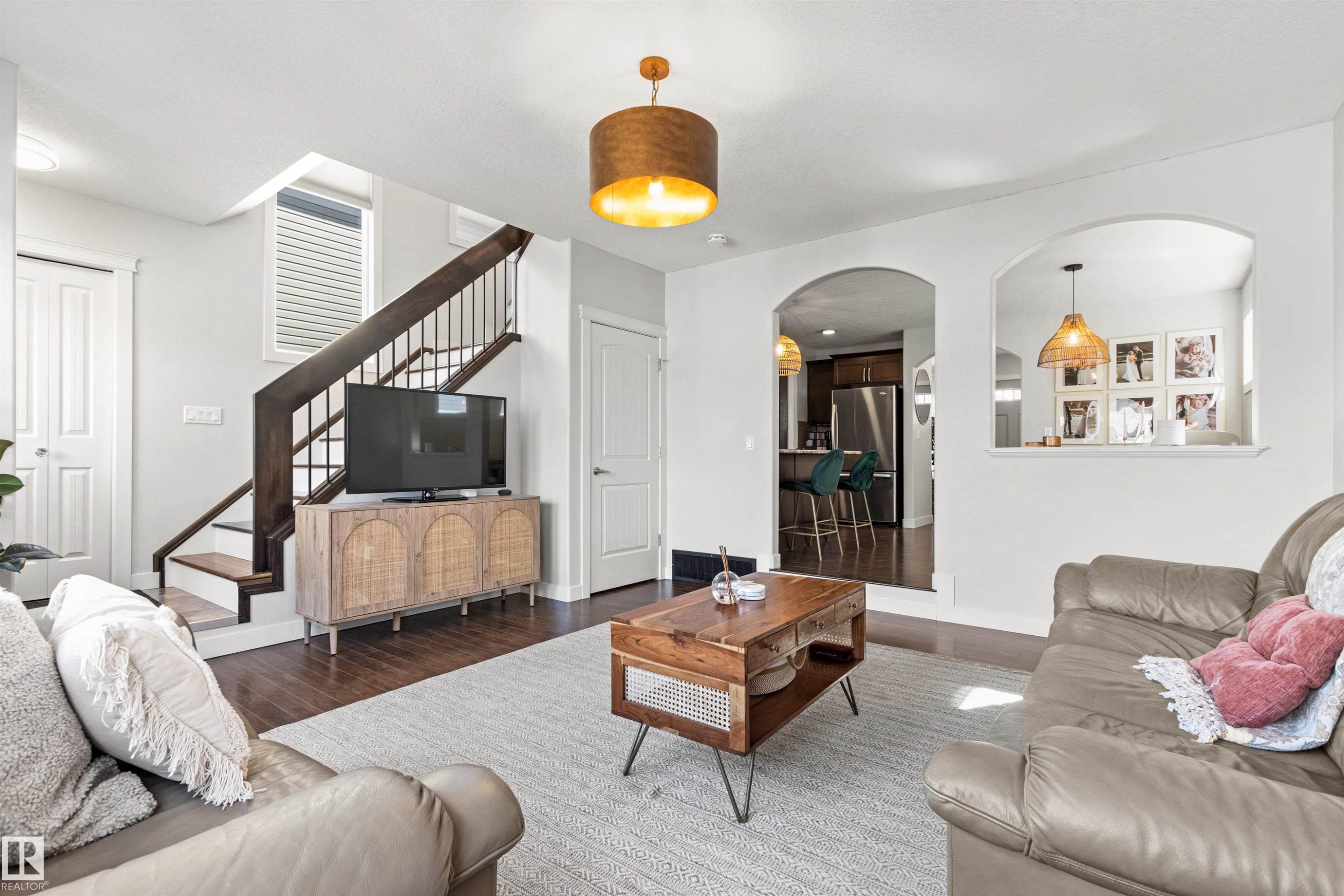 Living room featuring dark wood floors, white walls, and a staircase with dark wood banisters - 38 Hewitt Circle, Spruce Grove, AB - Indoor Photo Showing Living Room