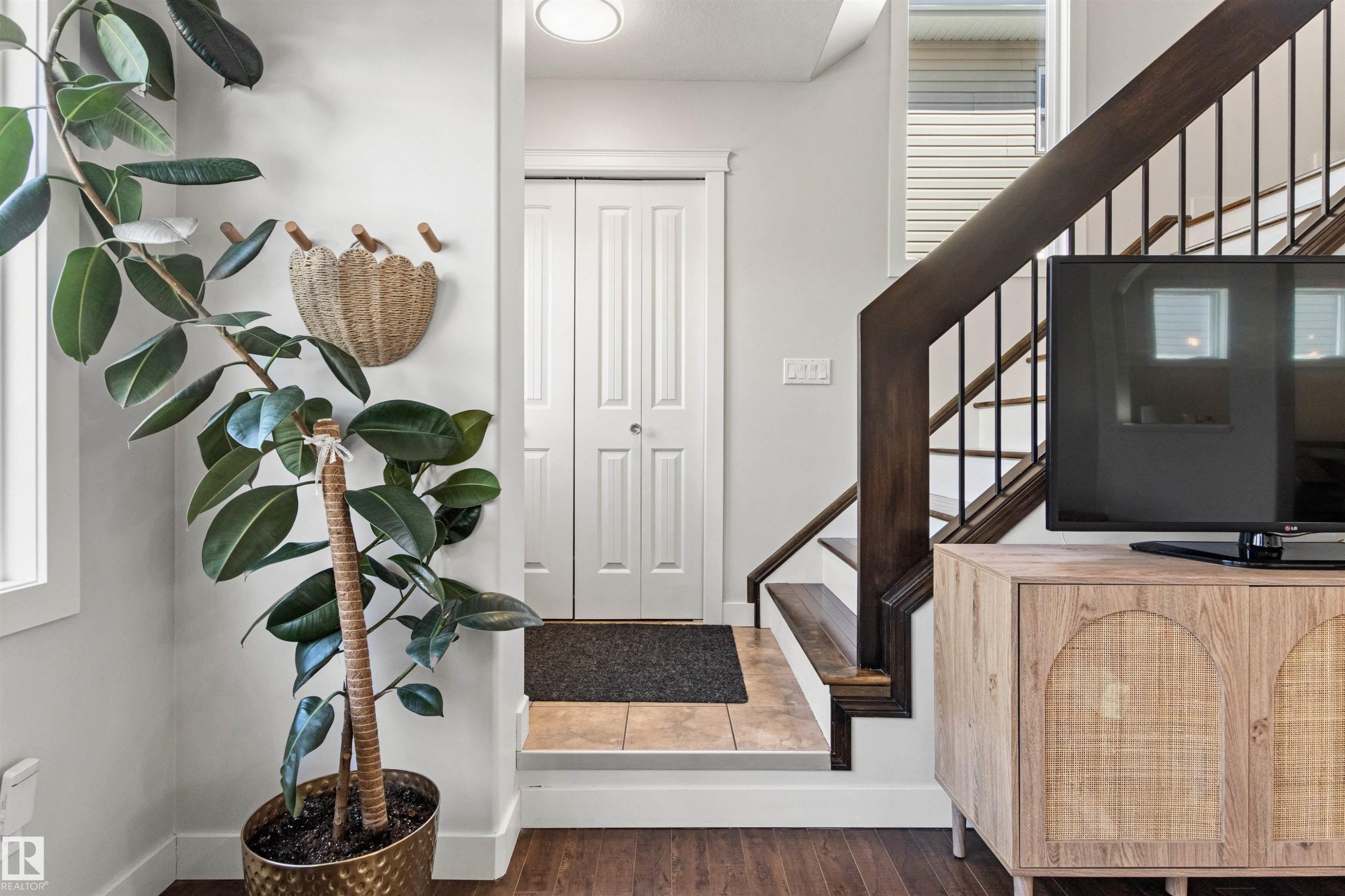 Entryway featuring hardwood flooring, a white paneled door, and a staircase with dark wood handrails and black balusters - 38 Hewitt Circle, Spruce Grove, AB - Indoor Photo Showing Other Room