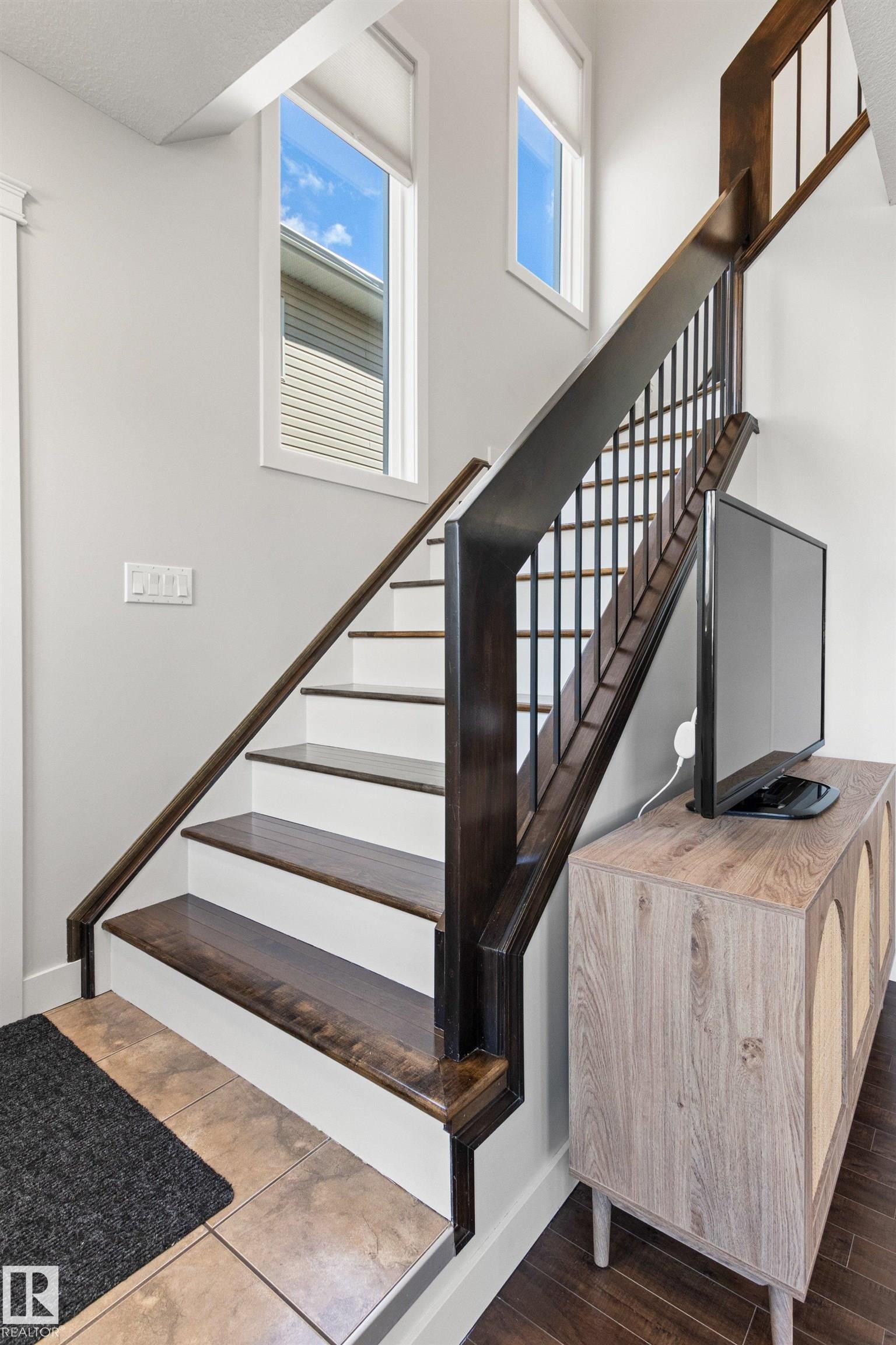 The property features a staircase with dark wood treads and handrails, complemented by white risers - 38 Hewitt Circle, Spruce Grove, AB - Indoor Photo Showing Other Room