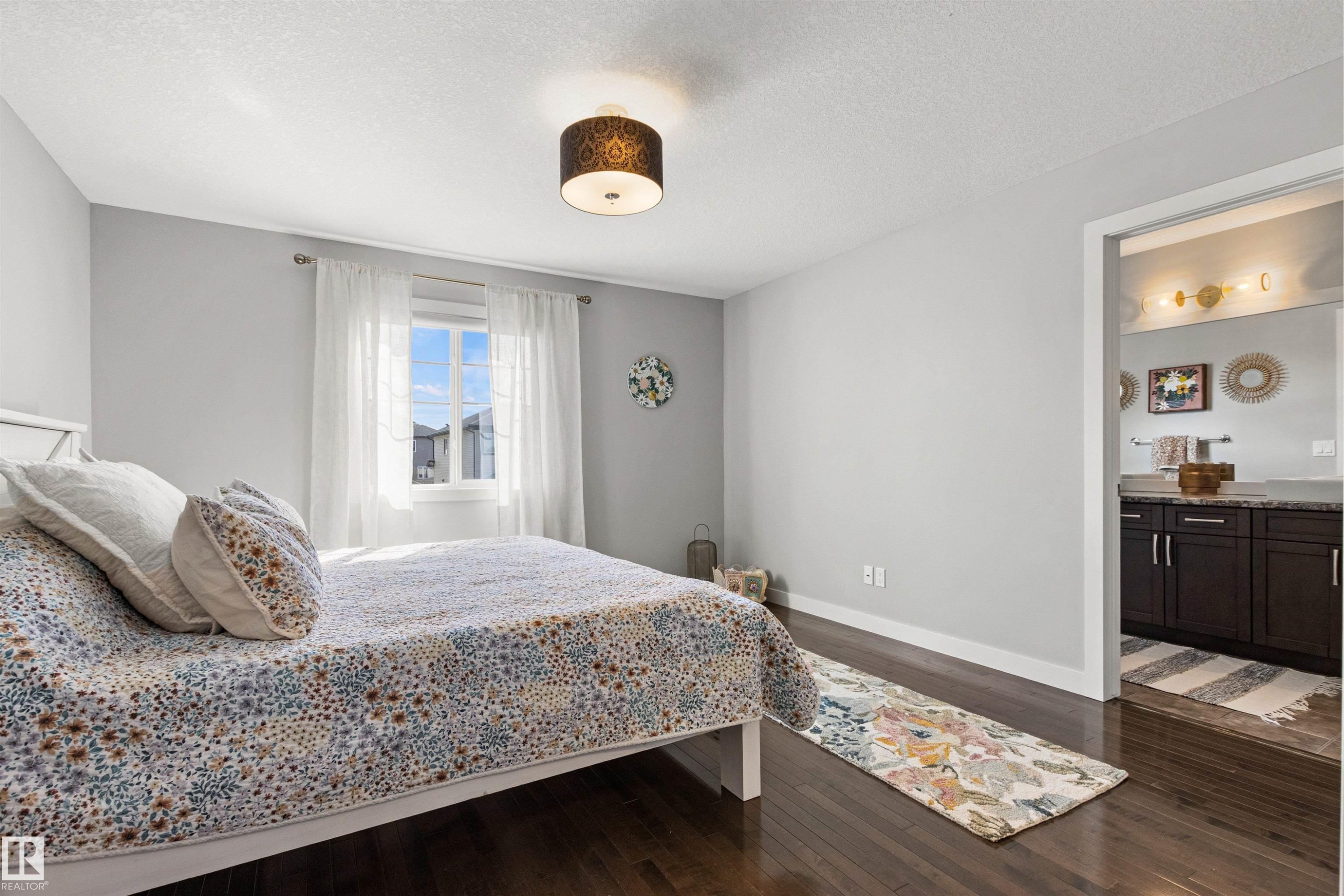 This inviting room features dark hardwood flooring and light-colored walls, providing a neutral backdrop - 38 Hewitt Circle, Spruce Grove, AB - Indoor Photo Showing Bedroom